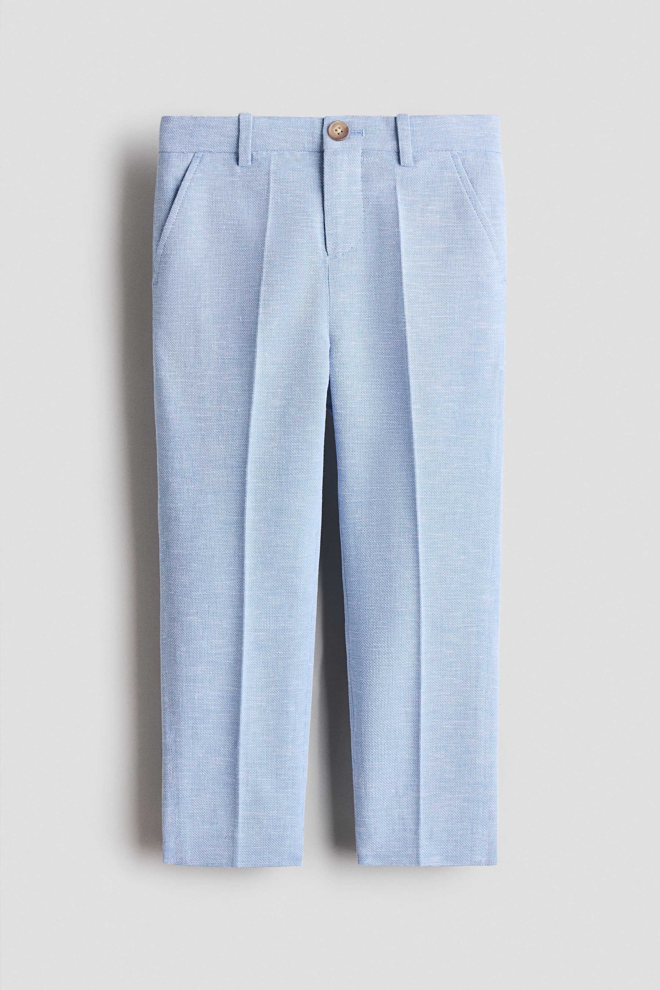 View larger image: Slim fit suit trousers in a light blue cotton weave are showcased by FRONT, featuring a single button fastening at the waist, slanted side pockets, and distinct creases running down the front of the legs.
