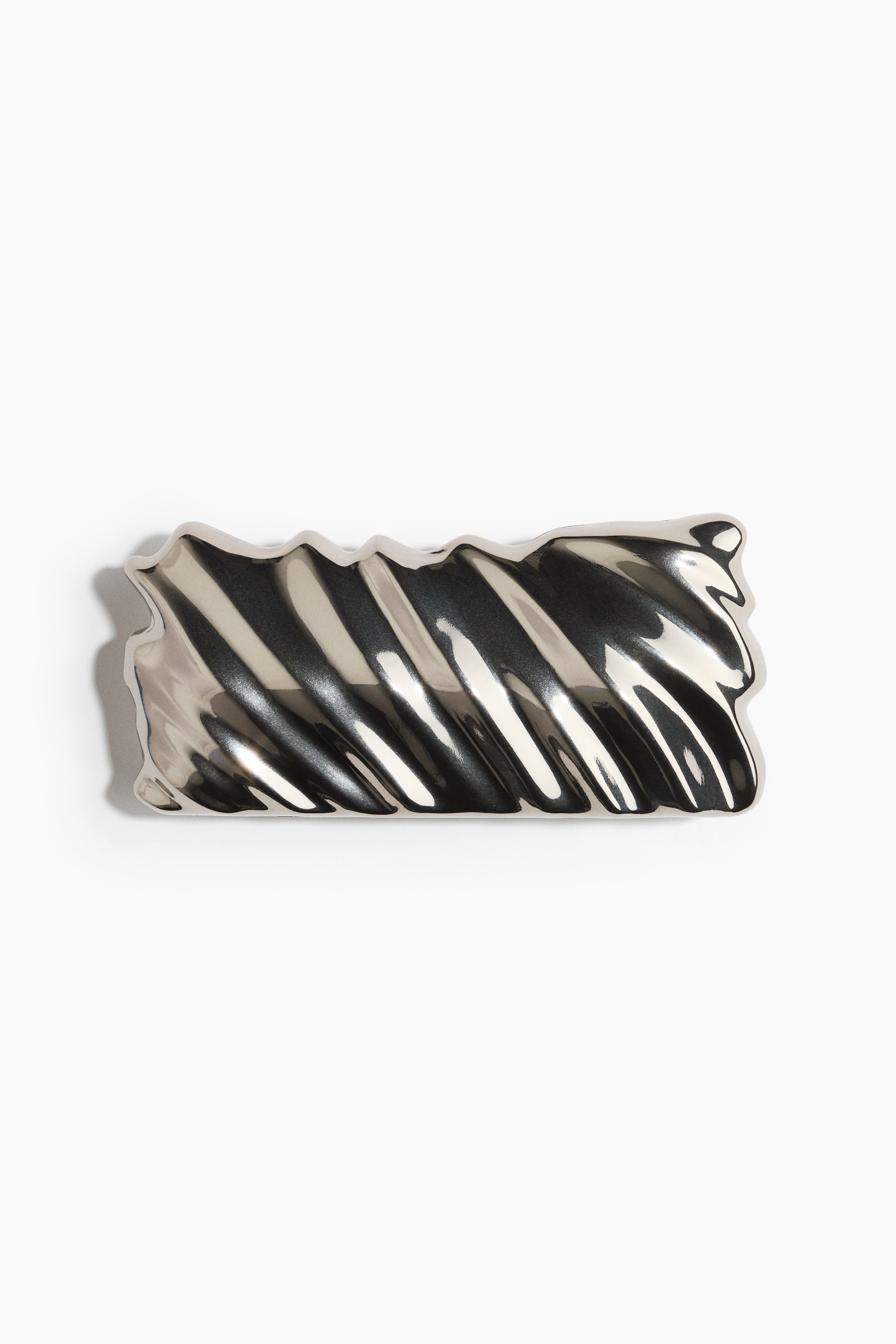 View larger image: A silver-toned metal barrette is shown in a rectangular shape with wavy, scalloped edges and a highly polished, reflective finish. The front-facing accessory features diagonal, dimensional ridges running across its surface, creating a rippled, liquid-like texture.
