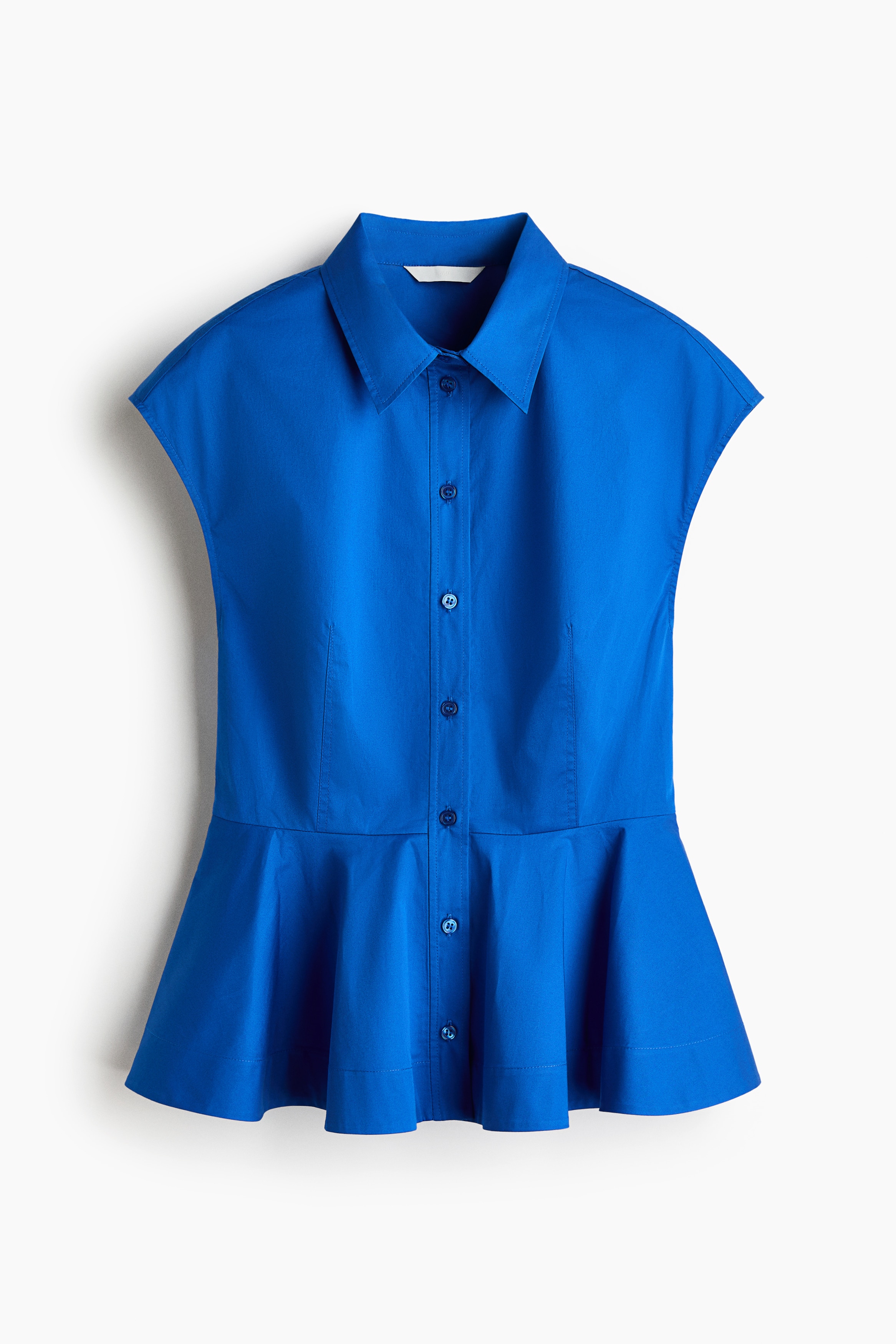A bright blue sleeveless top featuring a collar, button-down front, and flared peplum hem is worn by the model. The top is styled with wide-leg blue denim jeans.