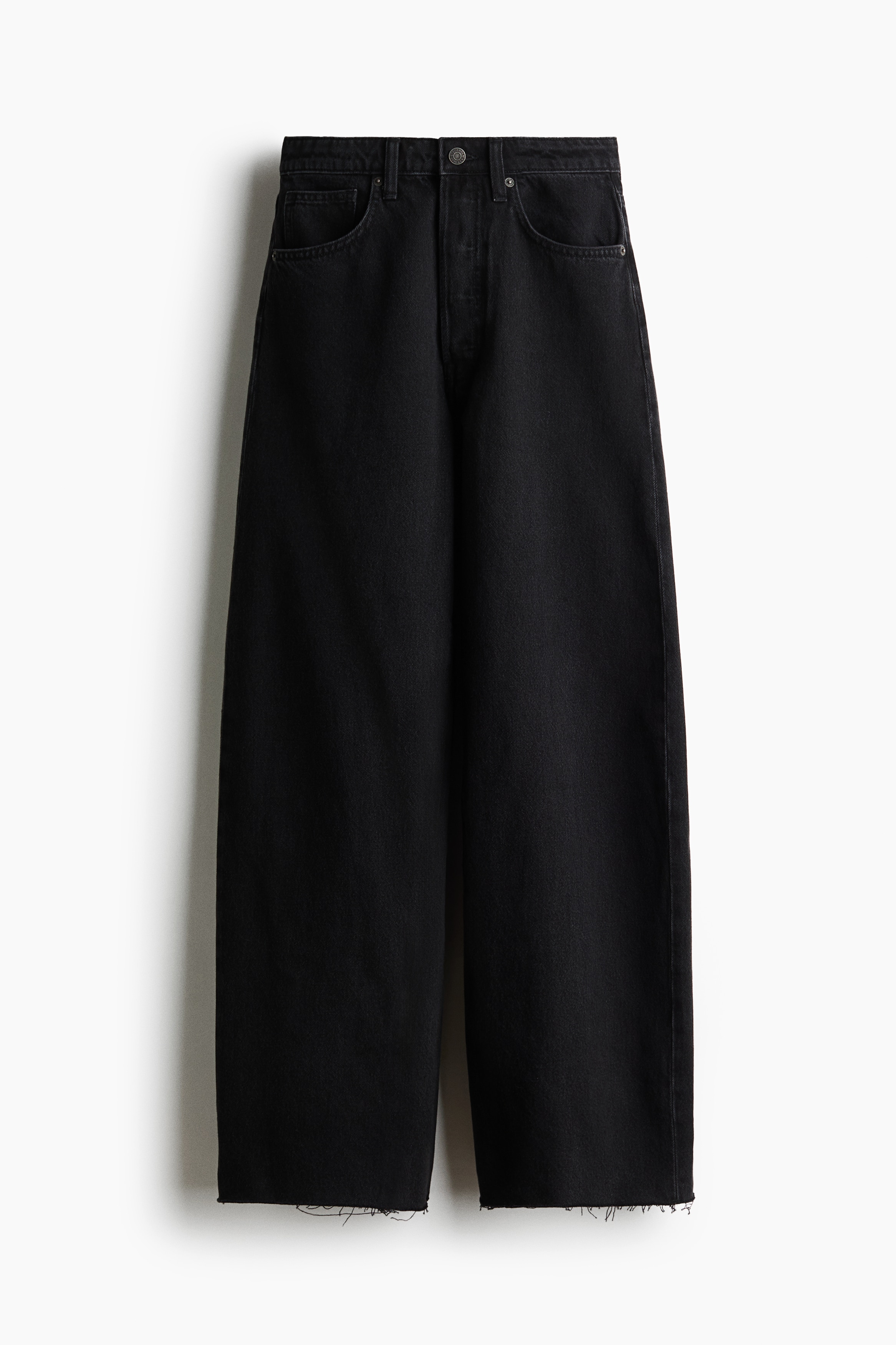 MÃ¸rkegrÃ¥, hÃ¸jttaljede denimjeans med en afslappet, tilspidset pasform bÃ¦res af modellen. Jeansen er stylet med en voluminÃ¸s, bÃ¦ltebetonet mÃ¸rkebrun lÃ¦derjakke og en cremefarvet top.