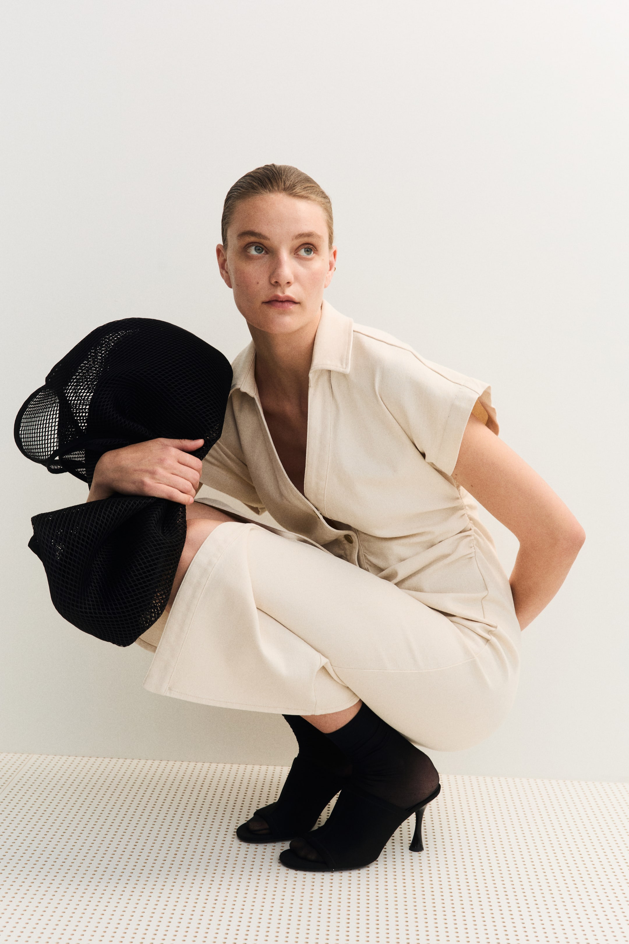 Ver imagem maior: Um vestido comprido e justo de ganga apresenta uma gola aberta, botões na frente e mangas curtas. Pregas nas laterais da cintura criam um efeito suavemente drapeado e uma silhueta ajustada.