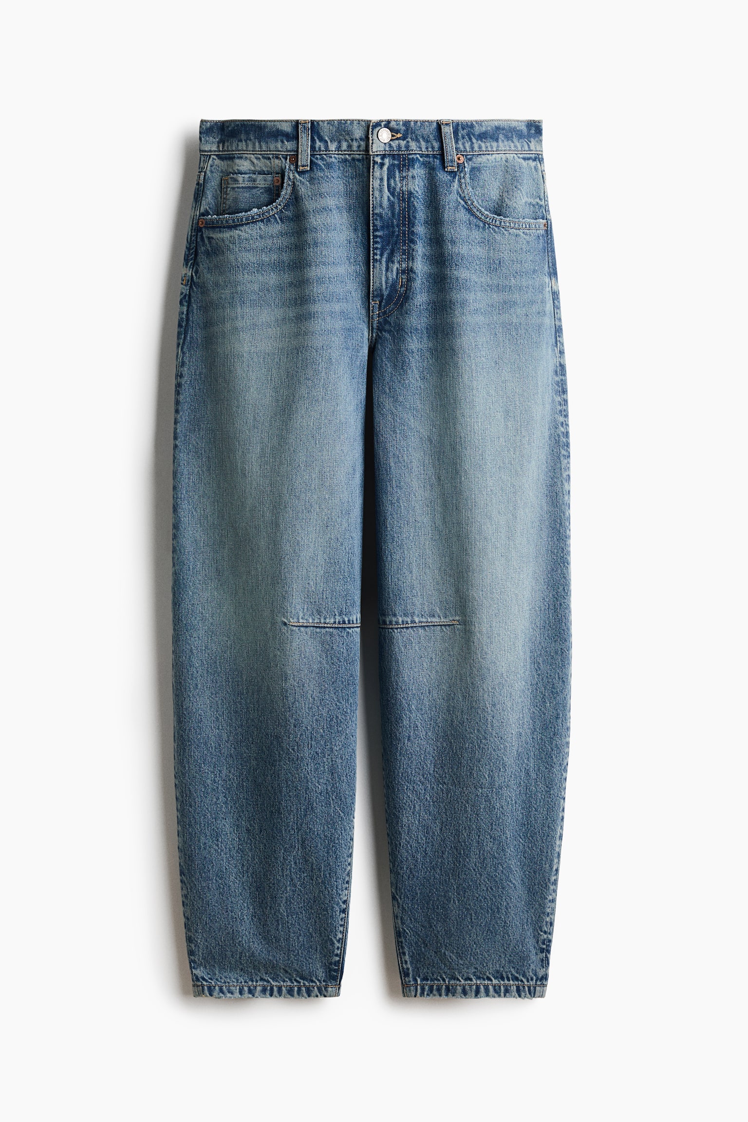 A pair of medium-wash blue denim jeans is hanging front-facing, featuring a voluminous, curved-leg silhouette that tapers toward the hem. The jeans feature horizontal knee darts, classic five-pocket styling, and a regular waist with a button closure.
