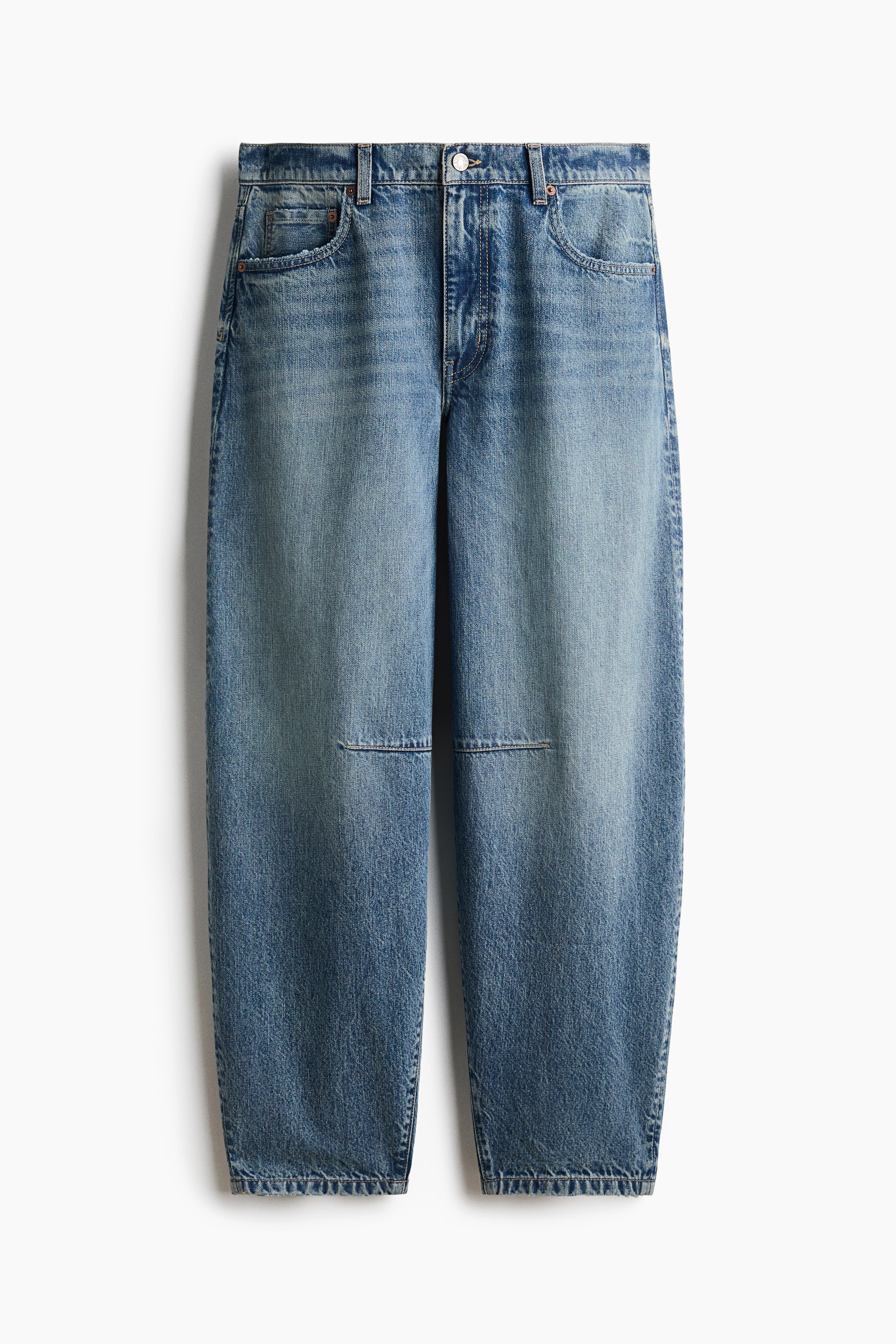 View larger image: A pair of medium-wash blue denim jeans is hanging front-facing, featuring a voluminous, curved-leg silhouette that tapers toward the hem. The jeans feature horizontal knee darts, classic five-pocket styling, and a regular waist with a button closure.