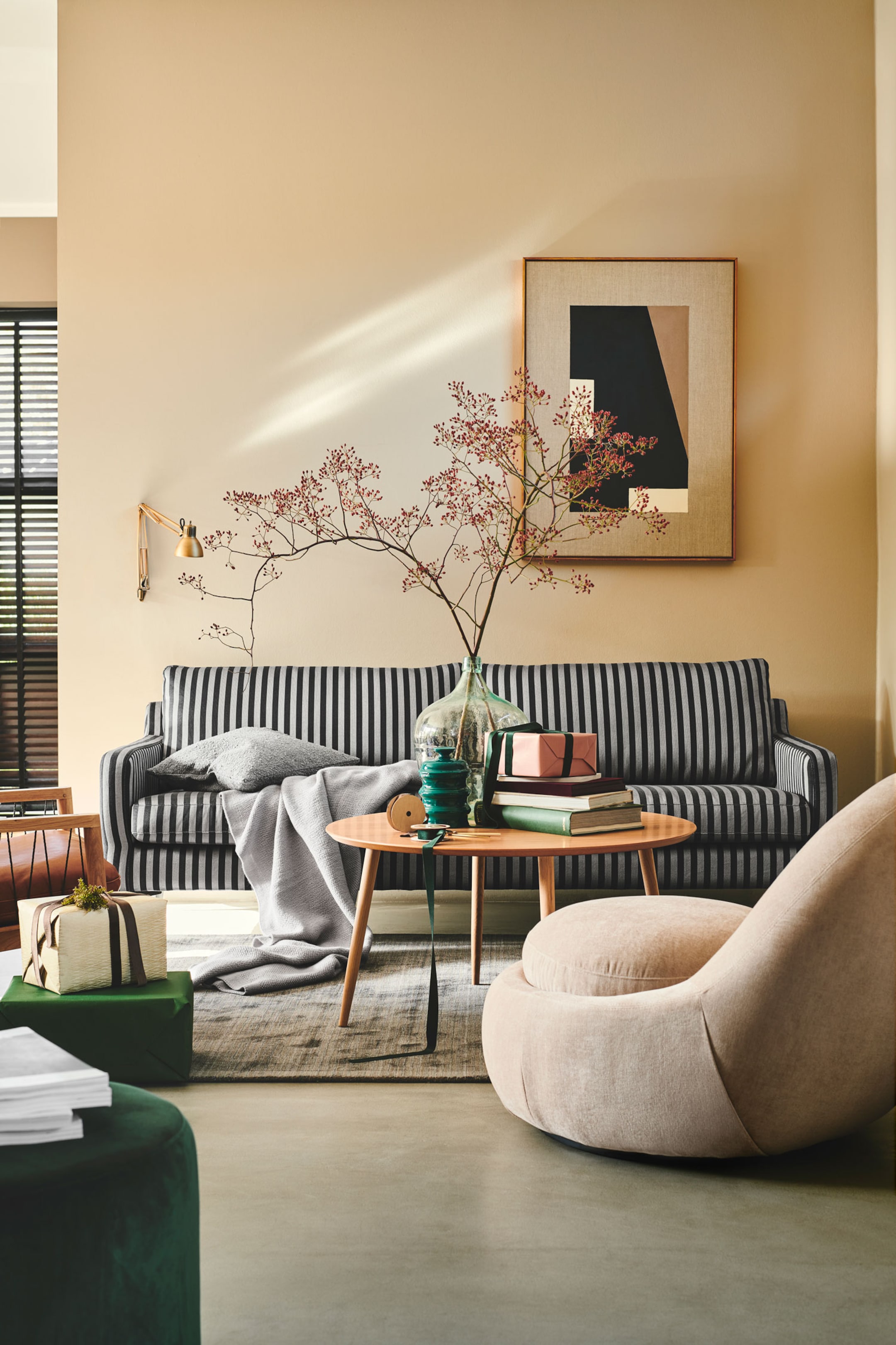 Größeres Bild ansehen: Ein Dreisitzer-Sofa mit vertikalem schwarz-grauem Streifenmuster ist mit einer grauen Kuscheldecke über der Sitzfläche und einem passenden grauen Zierkissen dekoriert.
