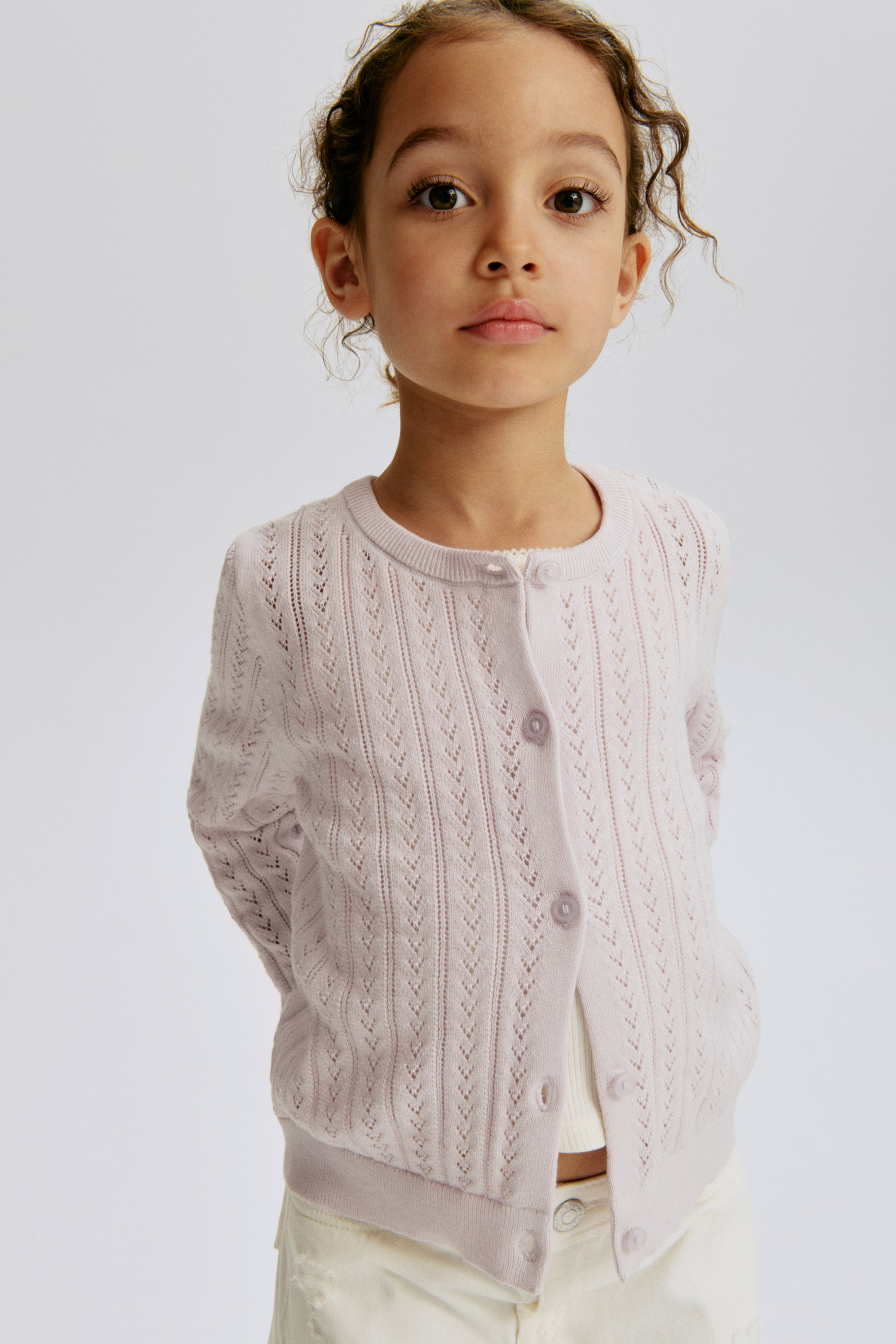 View larger image: A light purple, soft pointelle-knit cotton cardigan is facing forward, featuring a round, rib-trimmed neckline. It displays buttons down the front and ribbing at the cuffs and hem.