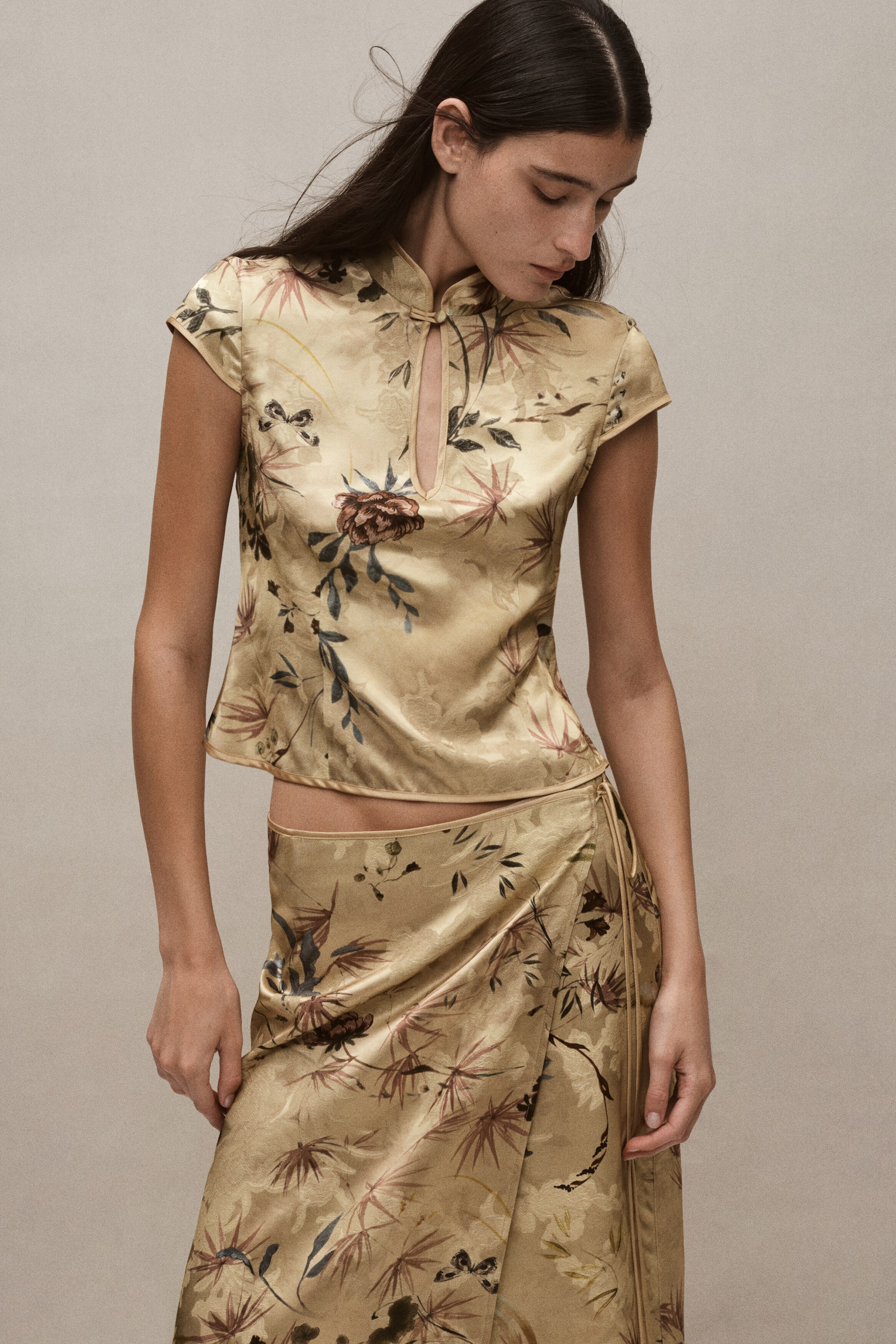 Má»t chiếc áo blouse jacquard tông và ng ÄÆ°á»£c chụp từ phÃa trưá»c, ná»i báºt vá»i há»a tiết hoa và chim nhiá»u mà u sắc. Thiết kế áo có cá» tà u, cà i bằng khuy móc phÃa trên chi tiết khoét giá»t lá» dá»c, cùng tay ngắn dạng cap sleeve và thân áo ôm dáng.