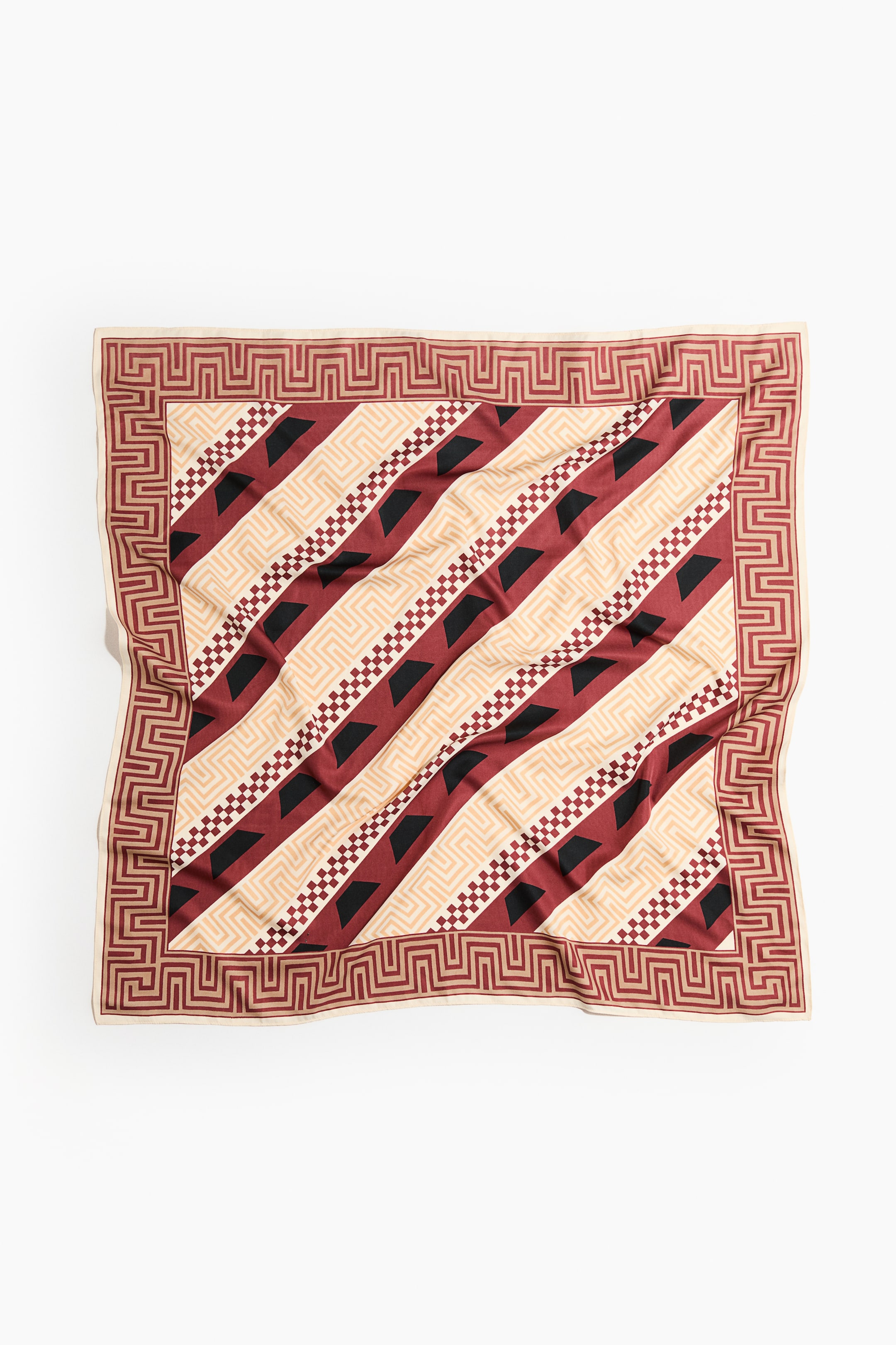 View larger image: A square scarf in a soft weave is laid flat, displaying a printed pattern. Its design is featuring a reddish-brown geometric border. The main body is showcasing diagonal bands that are alternating between solid reddish-brown with black irregular quadrilateral shapes, a cream color with a subtle maze-like geometric print, and a thinner band with a reddish-brown and cream checkered pattern.
