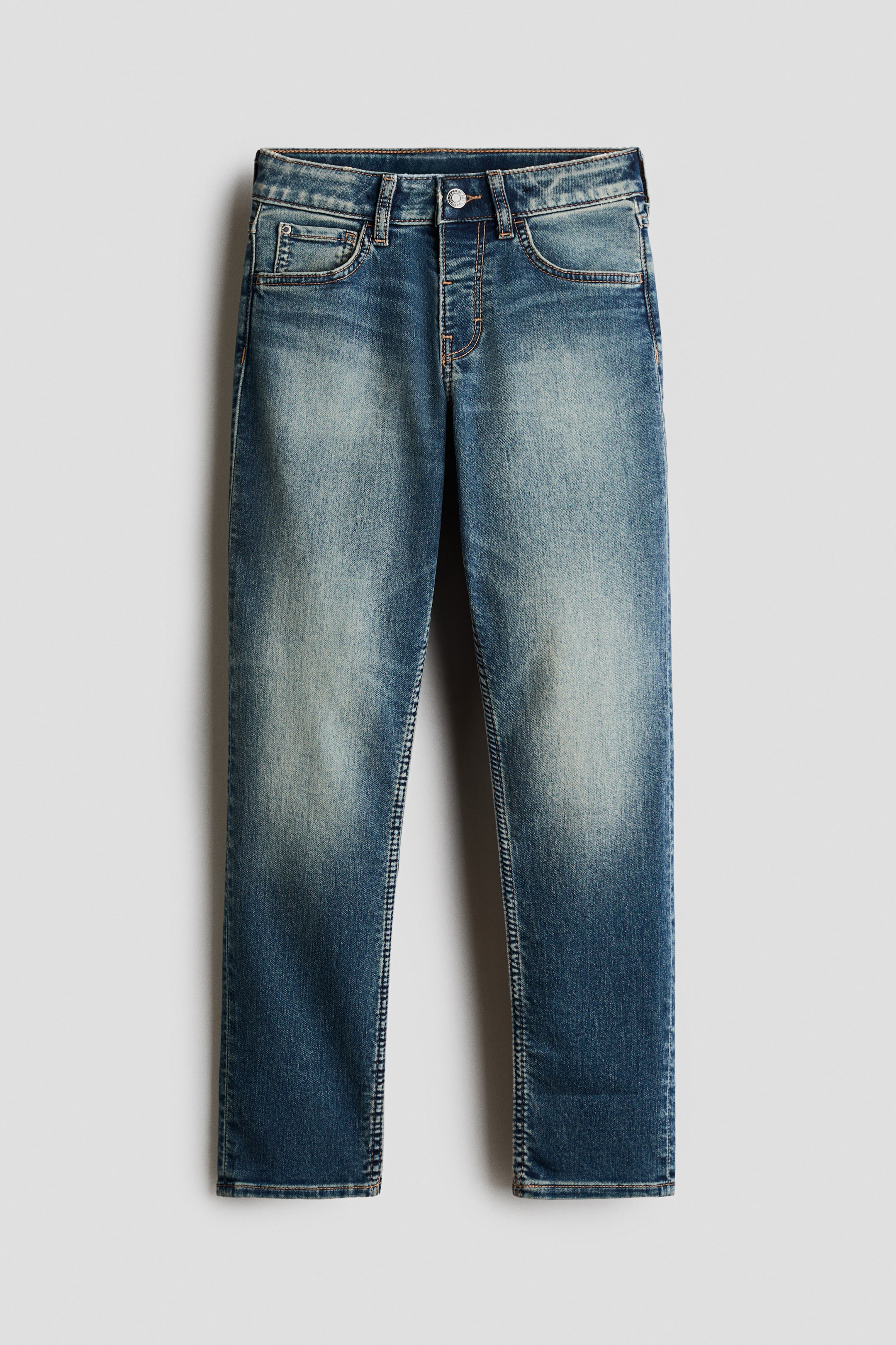 View larger image: Blue jeans are shown from the front, featuring a distressed medium wash with lighter fading on the thighs and knees. They are designed with a button fly closure, five belt loops, and classic five-pocket styling, including a small coin pocket and visible stitching.
