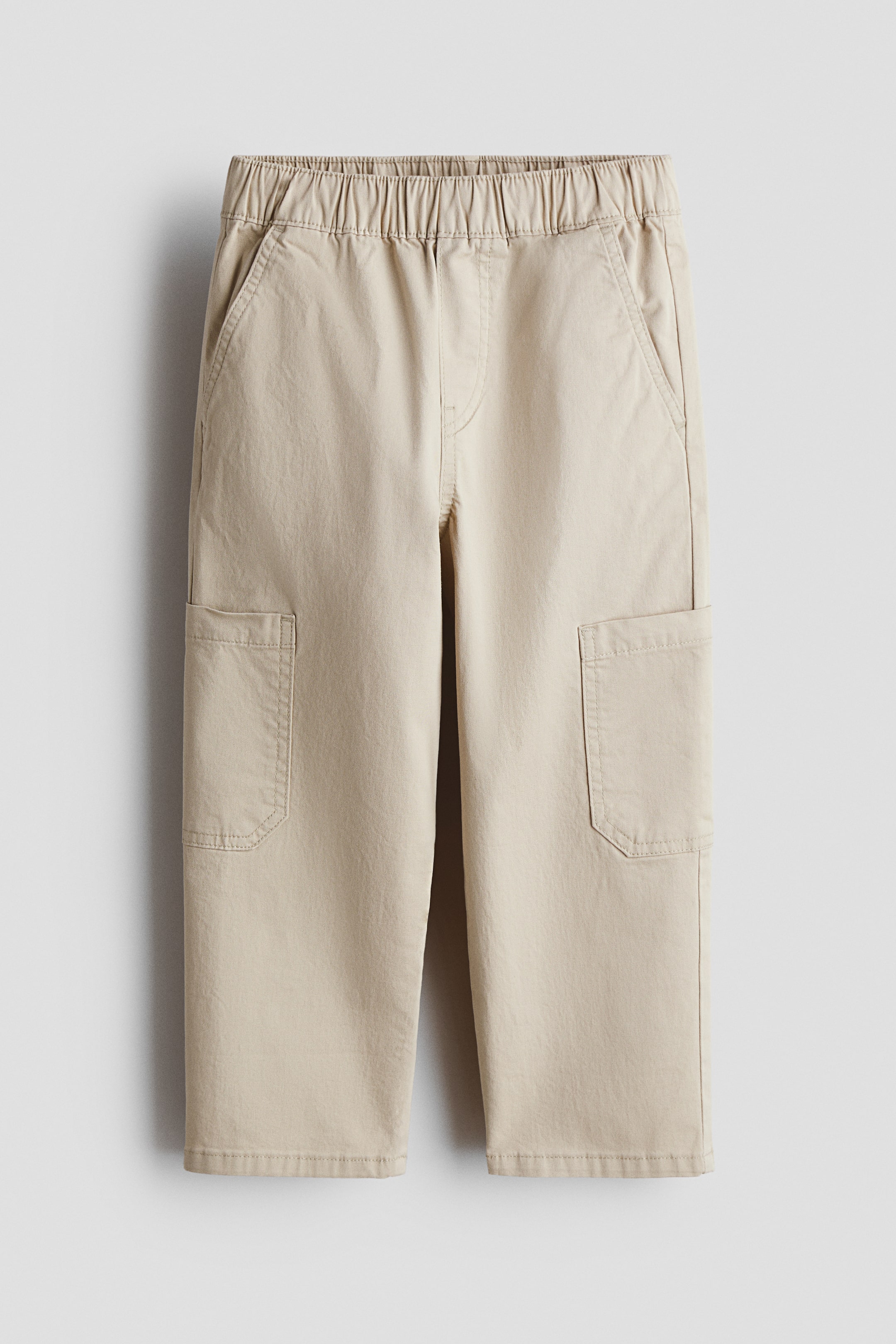 Vezi imaginea mai mare: Null pants sunt prezentate frontal, având o talie elastică, două buzunare laterale oblice și două buzunare aplicate mari, dreptunghiulare, poziționate pe mijlocul coapsei fiecărui picior drept.