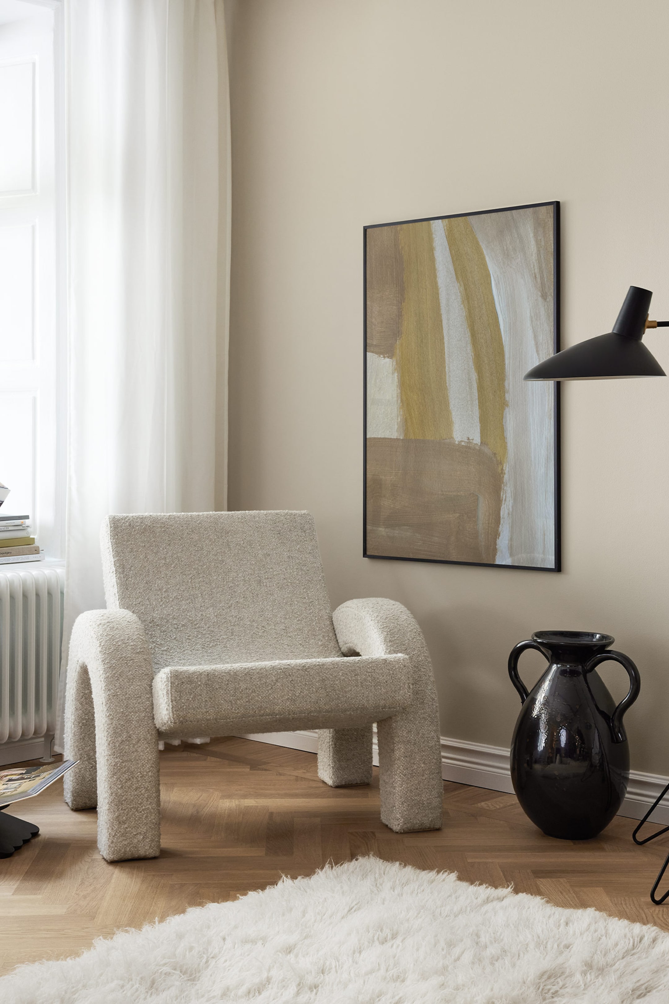 Grotere afbeelding bekijken: De fauteuil is voorzien van een licht crèmekleurige, gestructureerde bouclé stof. Het heeft een laag ontwerp met dikke, afgeronde armen en poten, en is iets naar rechtsvoor georiënteerd.