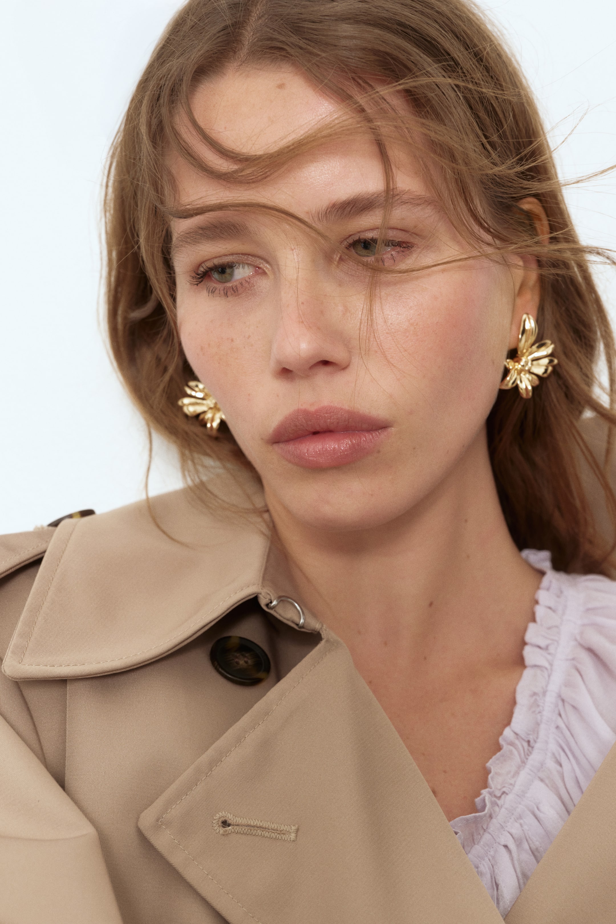 Voir une image plus grande: Boucles d'oreilles en forme de fleur en métal brillant portées par le mannequin.