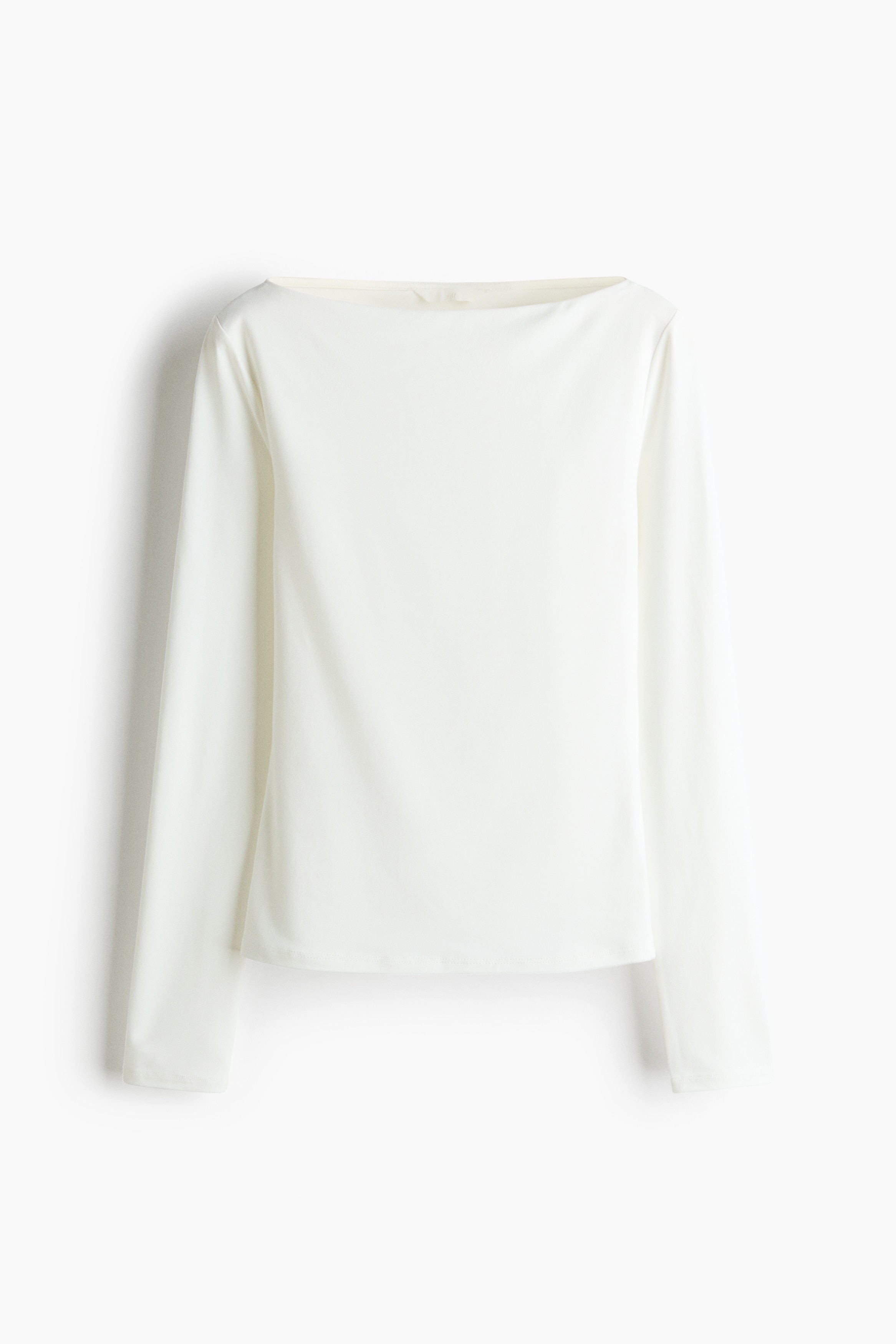 En hvit, figursydd topp i stretchjersey er vist forfra, med en ren bÃ¥thals og lange ermer. Toppen sitter tett inntil kroppen og er stylet nedi et par brune bukser.