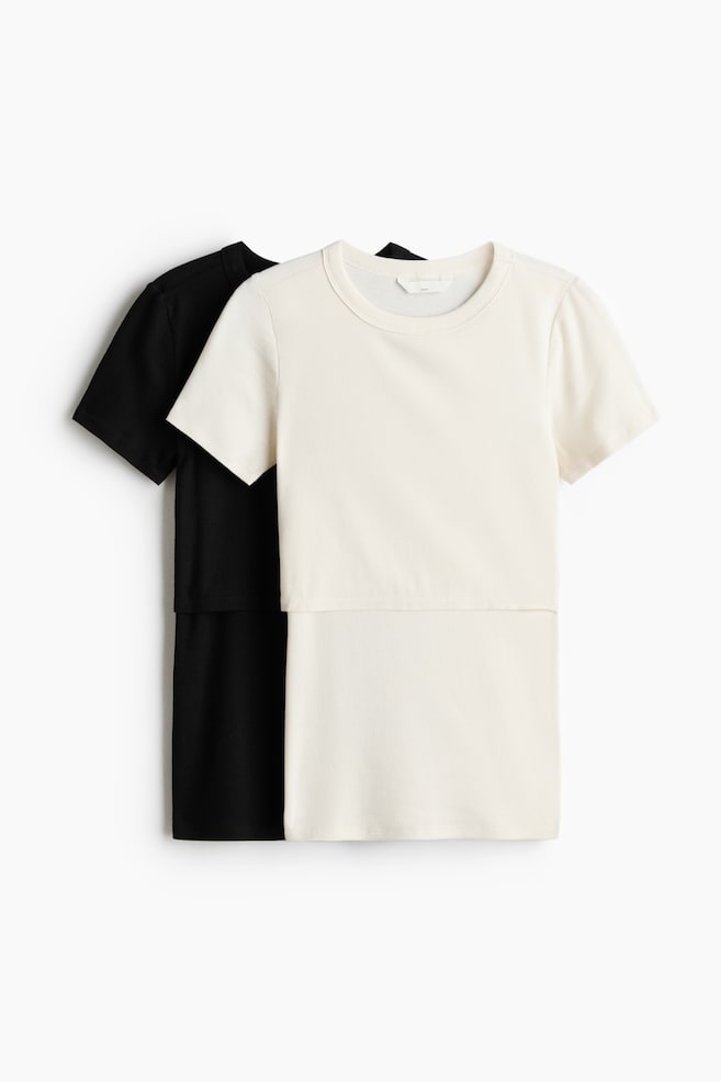 To kortermede ammetopper er vendt mot FRONT og har et dobbeltlagsdesign i front. Den kremfargede toppen, laget av ribbet bomullsjersey, overlapper delvis en svart topp av samme modell. - 1