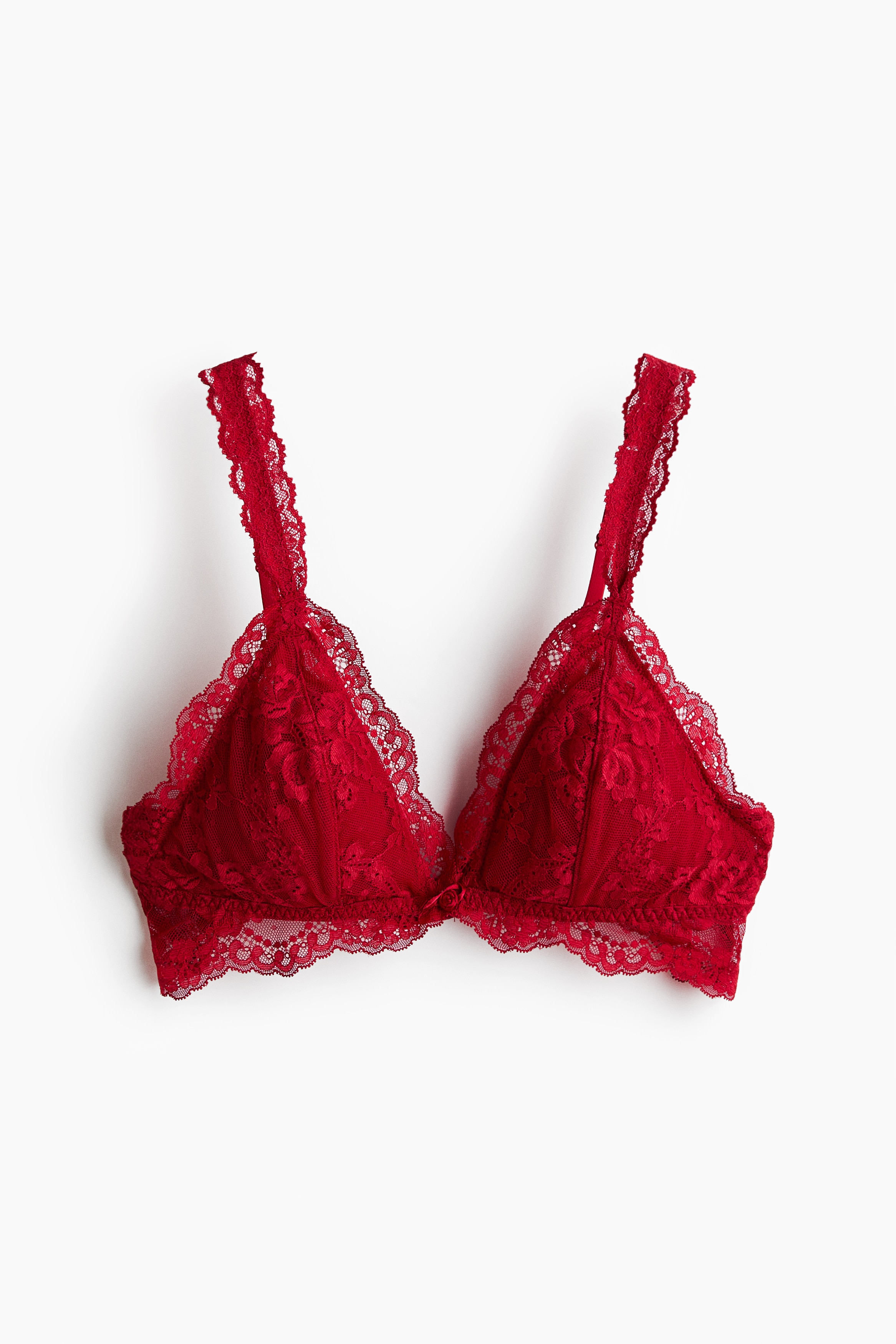 A red lace wireless bra with triangle cups, floral patterns, and scalloped trim is worn by the model. The close-up view highlights the lace-covered shoulder strap and a small decorative detail at the centre bust.