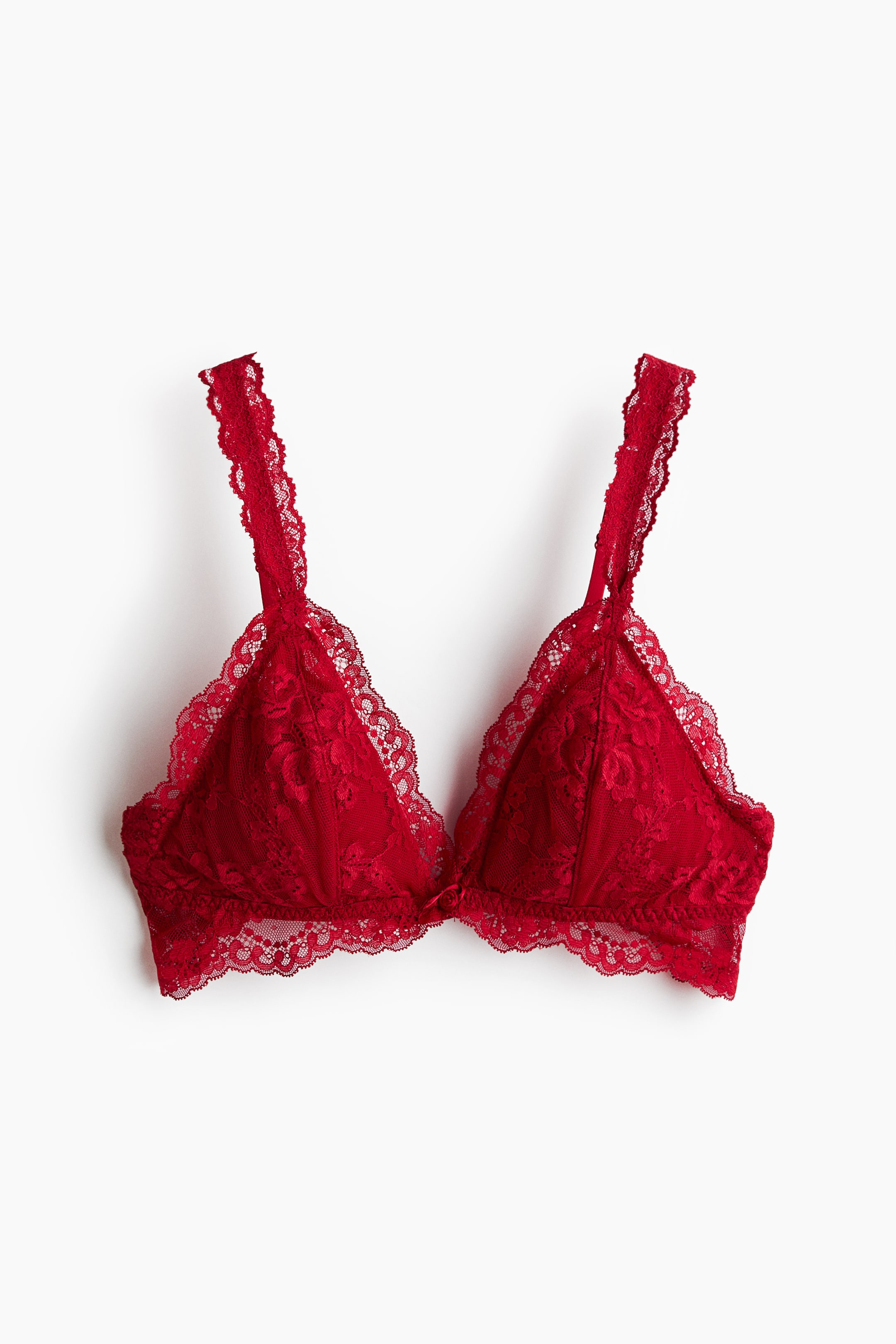 View larger image: A red lace bralette is shown from the front, showcasing triangular cups with an intricate floral lace pattern and scalloped edges. The design features matching lace-trimmed shoulder straps and a scalloped lace underband with a small bow detail at the centre.