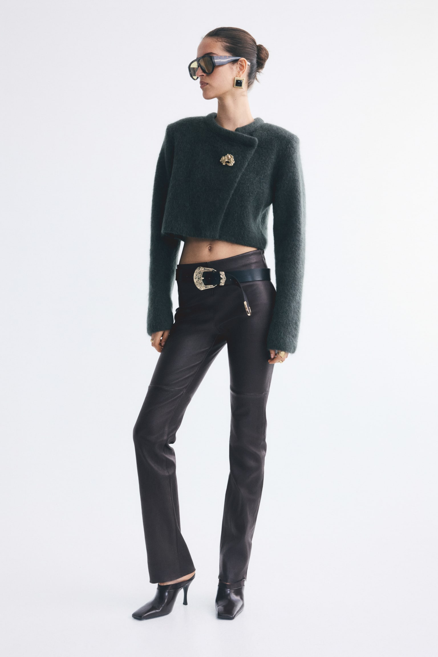 A pair of fitted, dark leather trousers is shown in a straight-leg silhouette from the front, featuring horizontal seams across the knees. The trousers have a smooth, flat waistband with a small concealed zip pull on the upper right side. - 1