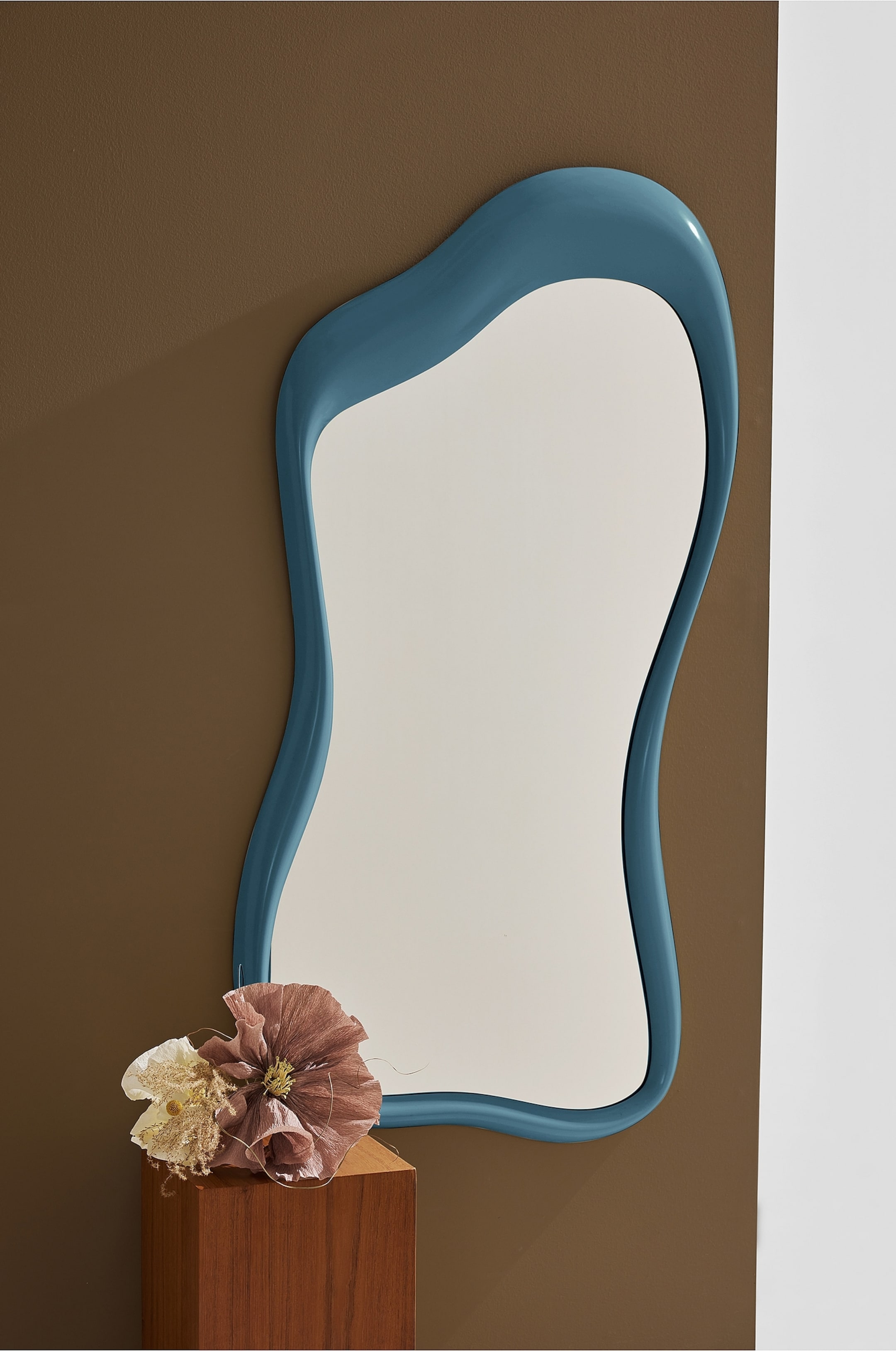 Agrandir l'image: Un miroir présente une forme irrégulière et organique avec un cadre lisse et brillant de couleur bleu sarcelle. Il est suspendu verticalement et fait face directement vers l'avant.