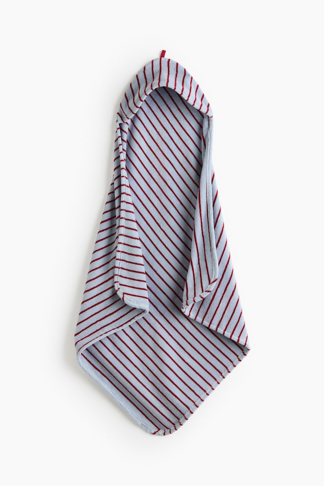 Uma toalha com capuz está pendurada, apresentando um tecido de algodão turquesa claro com riscas diagonais em vermelho escuro, e um capuz visível no topo. - 1