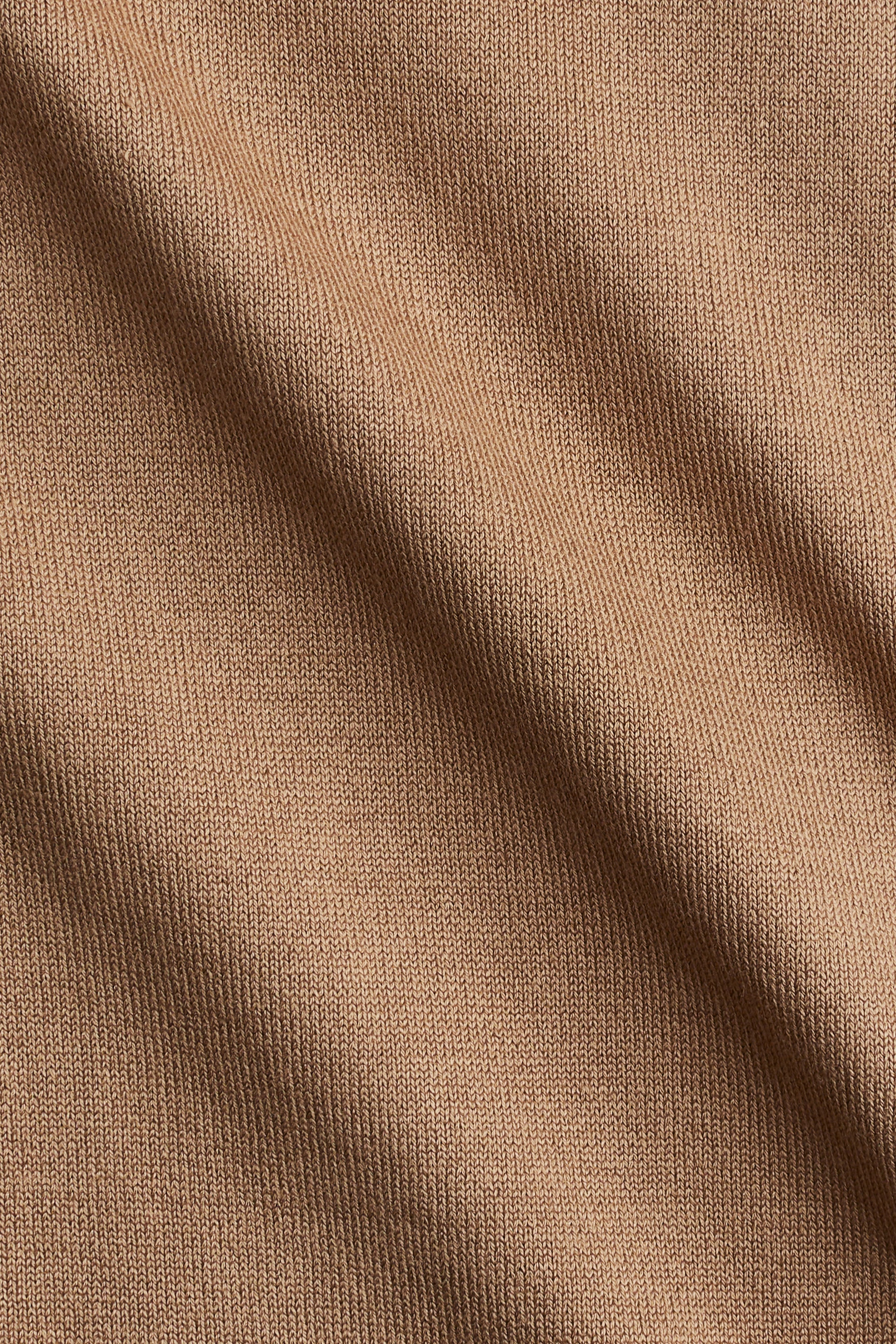 Xem ảnh lớn hơn: Một loại vải dệt kim có gân màu nâu nhạt đang hiển thị một họa tiết dọc đồng nhất, với các nếp gấp mềm mại tạo ra sự biến đổi trong bóng tối và ánh sáng.