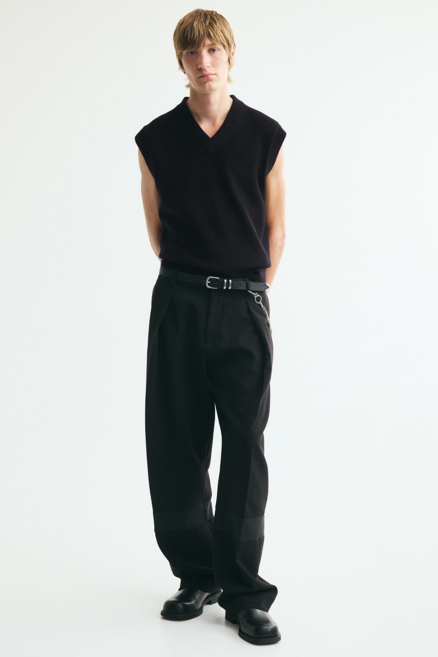 A black sleeveless jumper is facing front, featuring a V-neckline. It showcases a subtle, textured knit with ribbed trim along the V-neck, armholes, and straight bottom hem. - 1