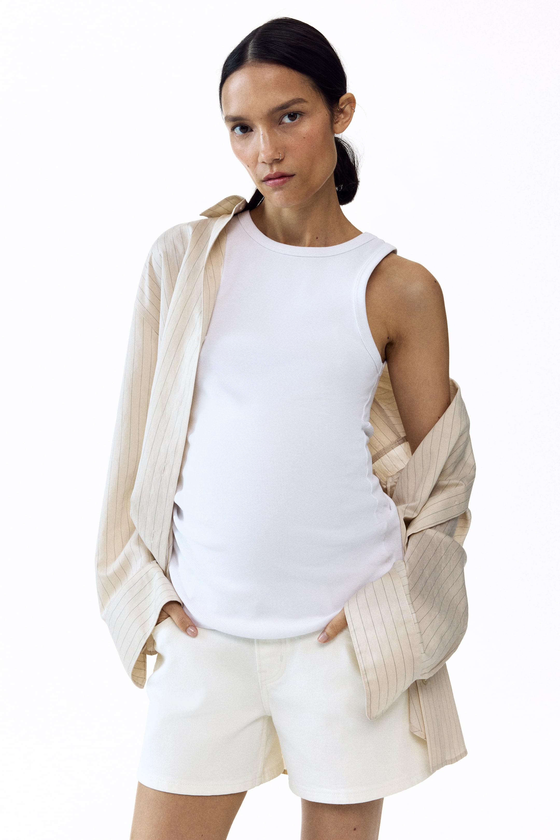 View larger image: The model is wearing light-coloured cotton denim shorts, with her hands tucked into the front pockets. These shorts boast a smooth, wide waistband, offering a comfortable fit.