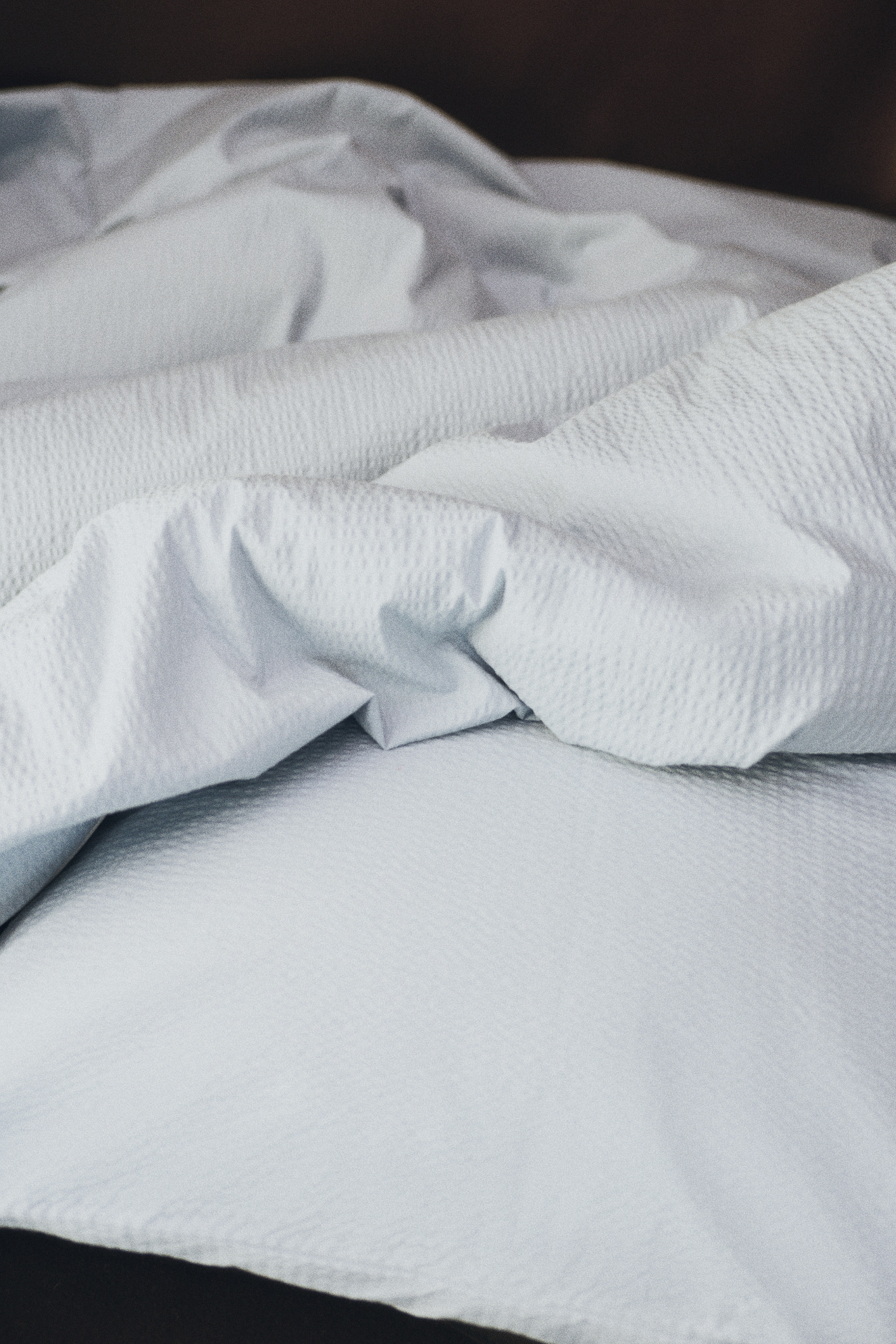 Un ensemble de housse de couette en seersucker bleu clair est présenté de face, avec une taie d'oreiller posée verticalement derrière une housse de couette soigneusement pliée. Les deux pièces affichent la texture froissée distinctive du tissu seersucker.