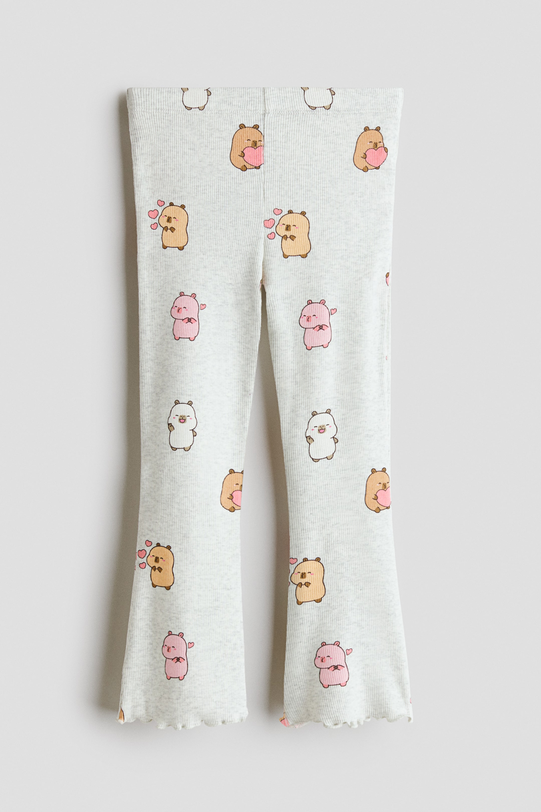 View larger image: The leggings are showcased in a front view, crafted from a light grey ribbed knit fabric adorned with an all-over pattern of cartoon bears holding pink hearts. The legs exhibit a slight flare at the bottom, with the hems elegantly finished with a delicate lettuce edge.