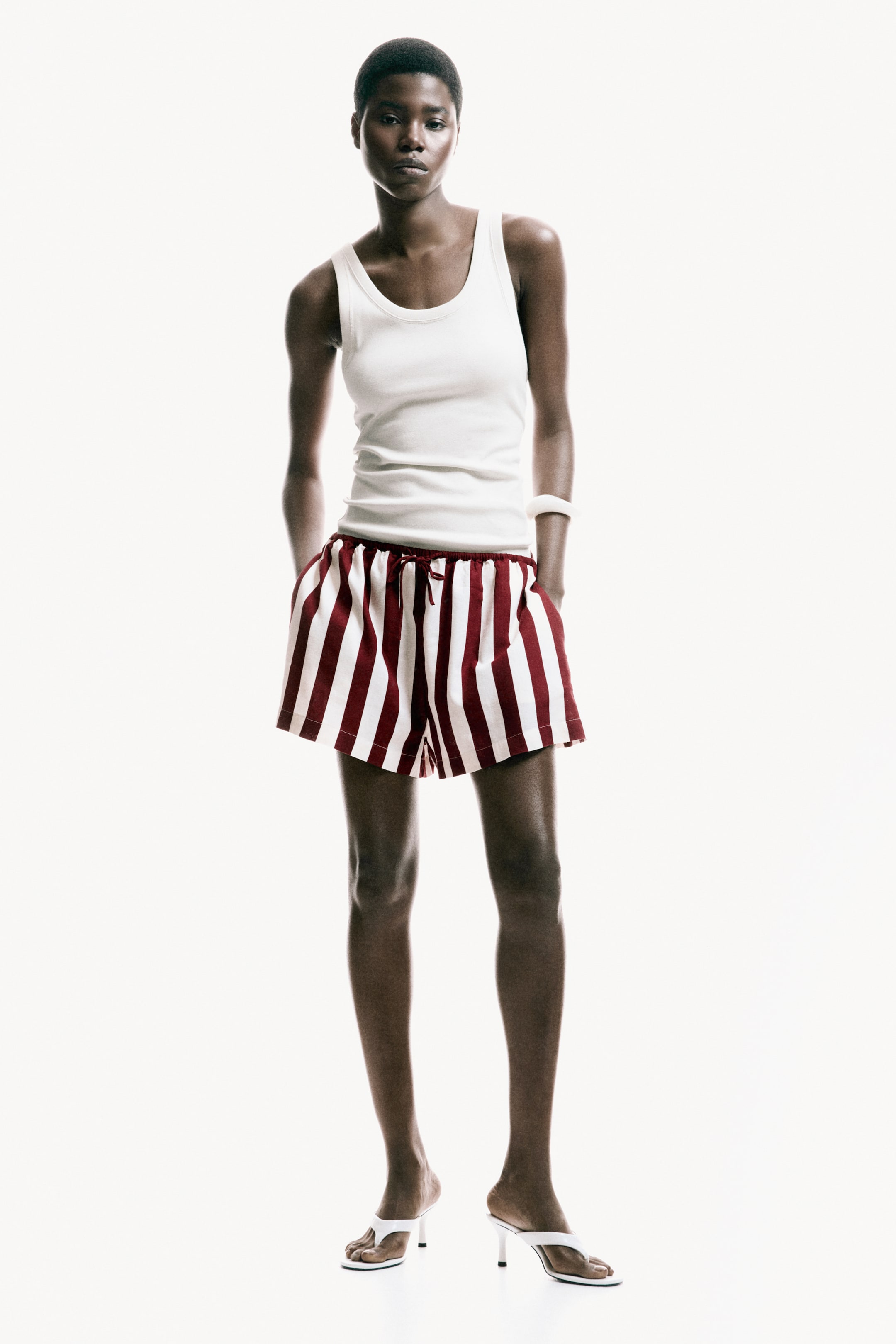 View larger image: A white ribbed vest is being worn, featuring a scoop neckline and a snug fit.