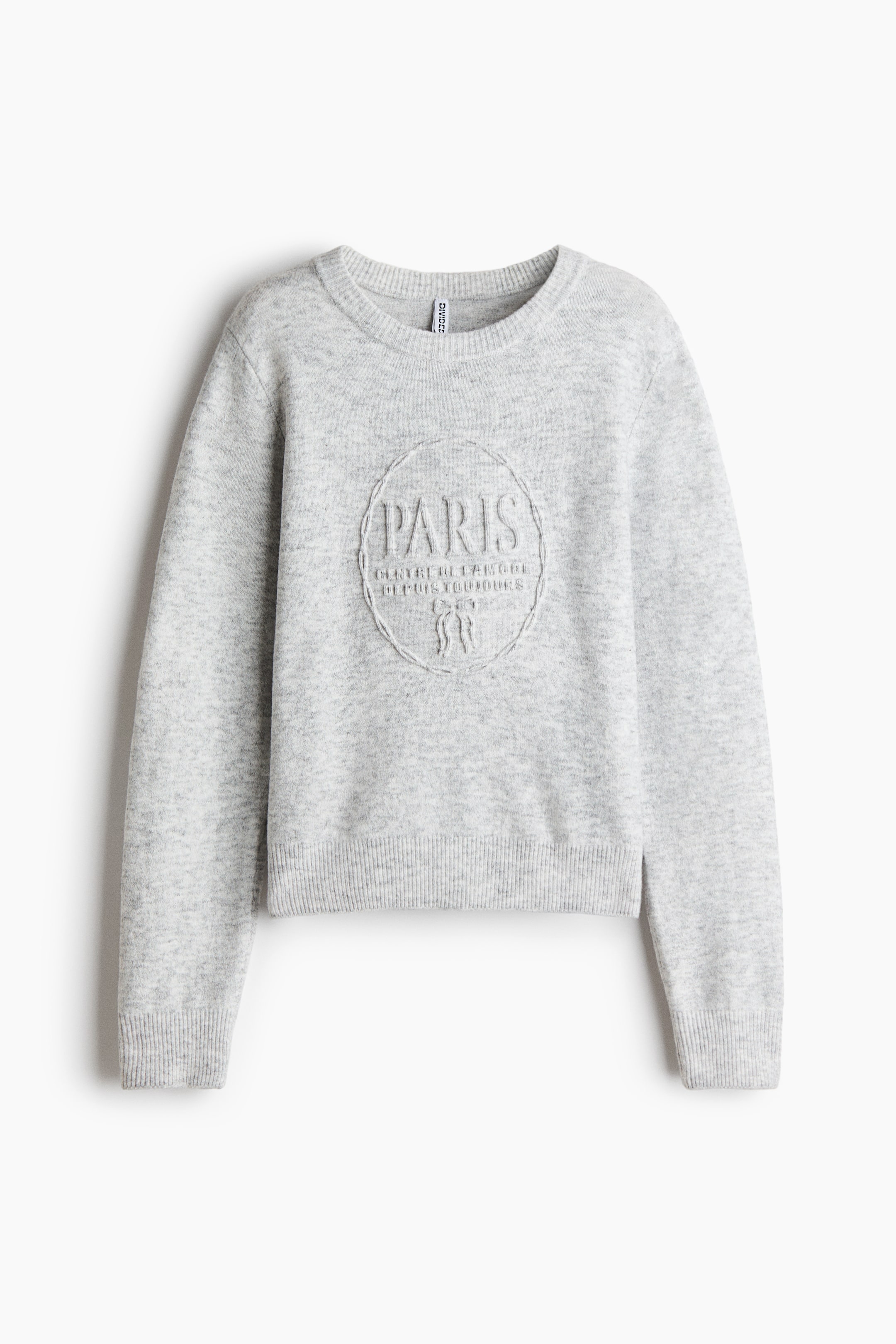 Ver imagen más grande: Un jersey de cuello redondo en gris claro muestra su parte frontal, con mangas largas, puños de canalé y bajo de canalé. En el pecho aparece un gráfico circular en relieve con la palabra "PARIS" en letras grandes, la frase "CENTRE DE LA MODE DEPUIS TOUJOURS" y un pequeño diseño de lazo debajo.