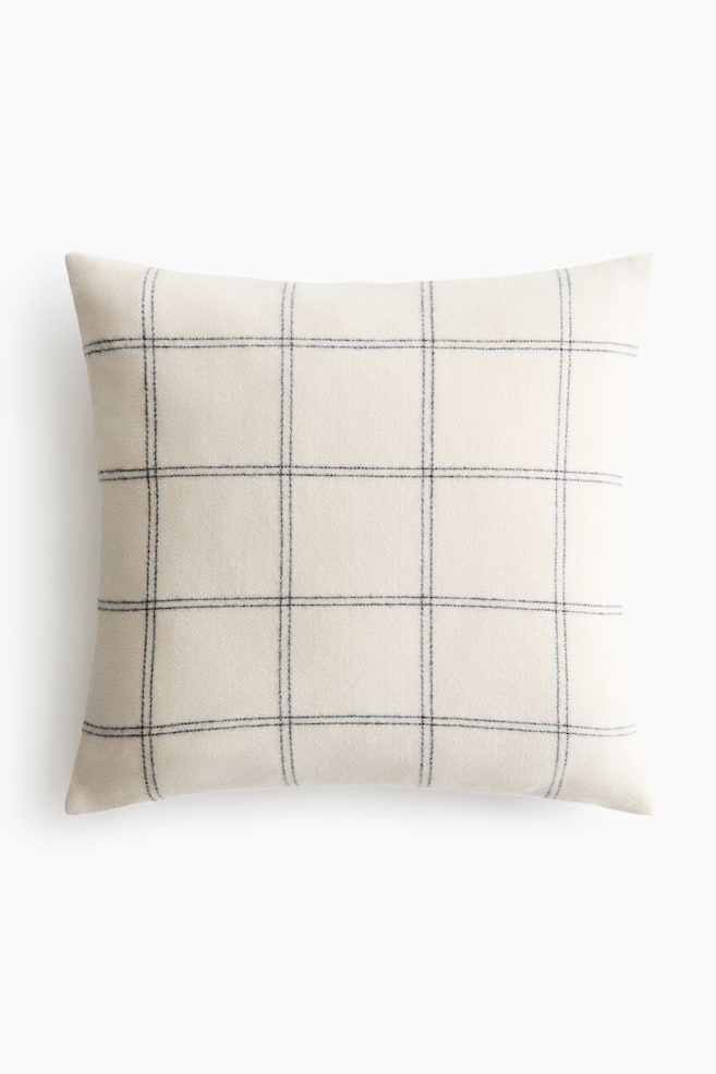 The square cushion showcases an off-white fabric adorned with a dark, subtly irregular windowpane plaid pattern. - 1