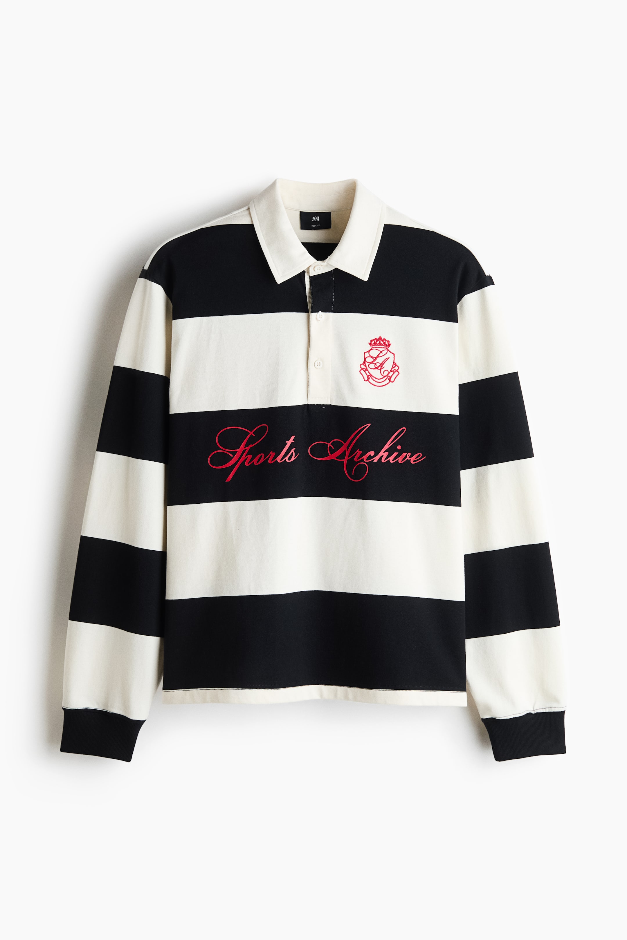View larger image: A long-sleeve rugby shirt is shown from the front, featuring bold horizontal black and off-white stripes, an off-white polo collar, and a partial button placket. The shirt displays red cursive text reading "Sports Archive" across the centre chest, a small red crest on the left breast, and long sleeves with black ribbed cuffs.