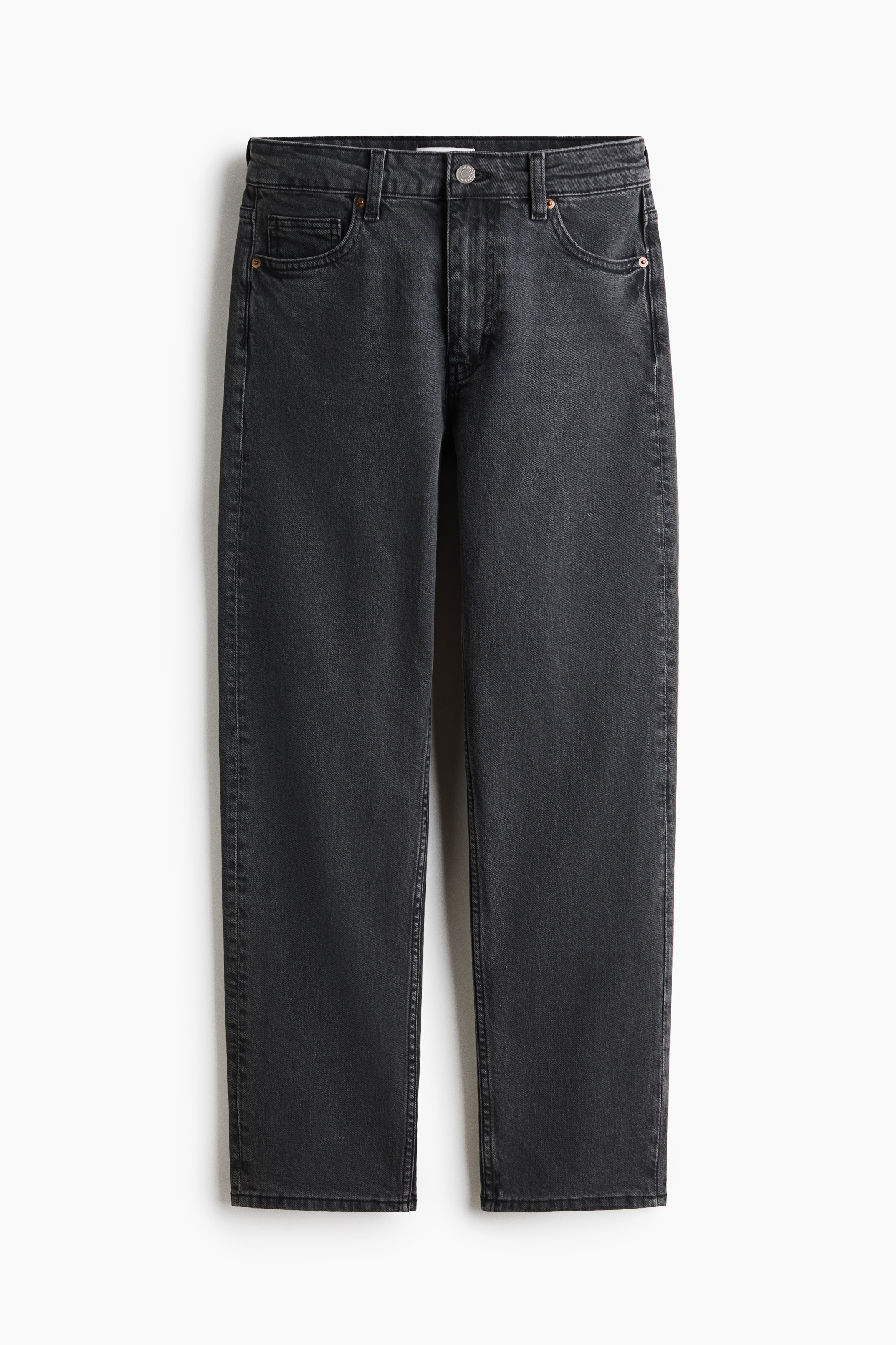 Dark grey, high-waisted jeans with five pockets and a tapered leg are worn by the model, who is standing. The jeans are paired with an oversized black shirt, which the model is holding back to reveal the fitted waist and button closure.