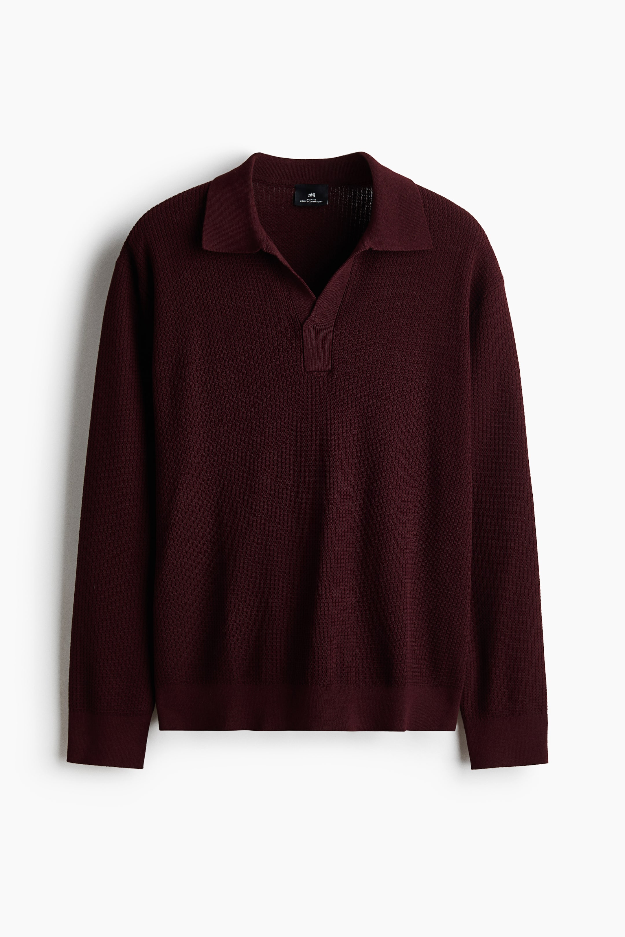 View larger image: A men's knit polo shirt is shown in a deep burgundy color with a textured waffle knit pattern. It features a classic polo collar, an open V-neck placket, long sleeves, ribbed cuffs, and a ribbed hem, presented in a front view.