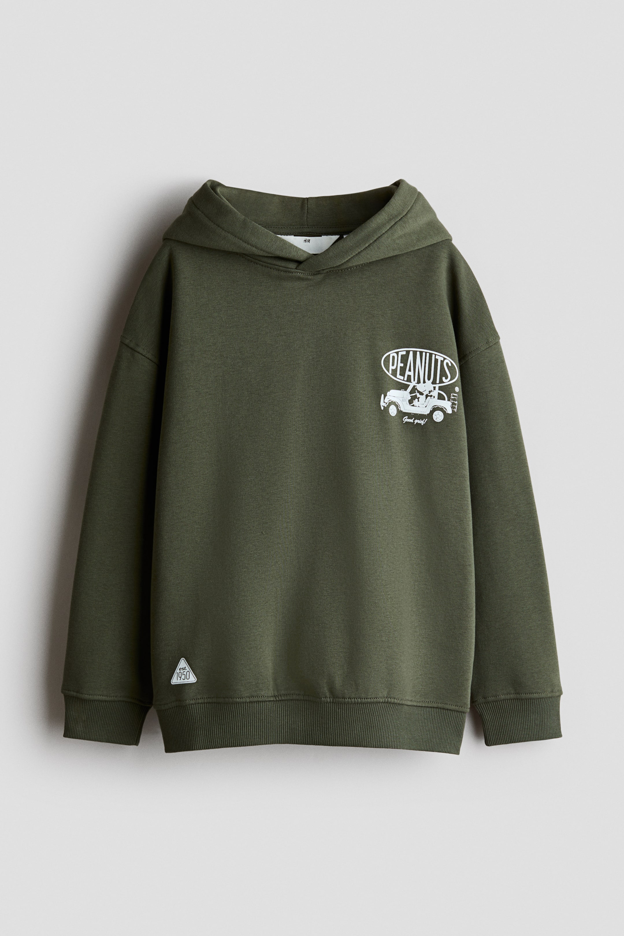 Größeres Bild ansehen: Ein locker geschnittener Hoodie in Olivgrün ist von vorne zu sehen und zeigt eine Wickelkapuze, überschnittene Schultern sowie gerippte Bündchen und einen gerippten Saum. Auf der linken Brust befindet sich ein weißer Grafikdruck, und am unteren rechten Saum ist ein kleines dreieckiges Patch angebracht.