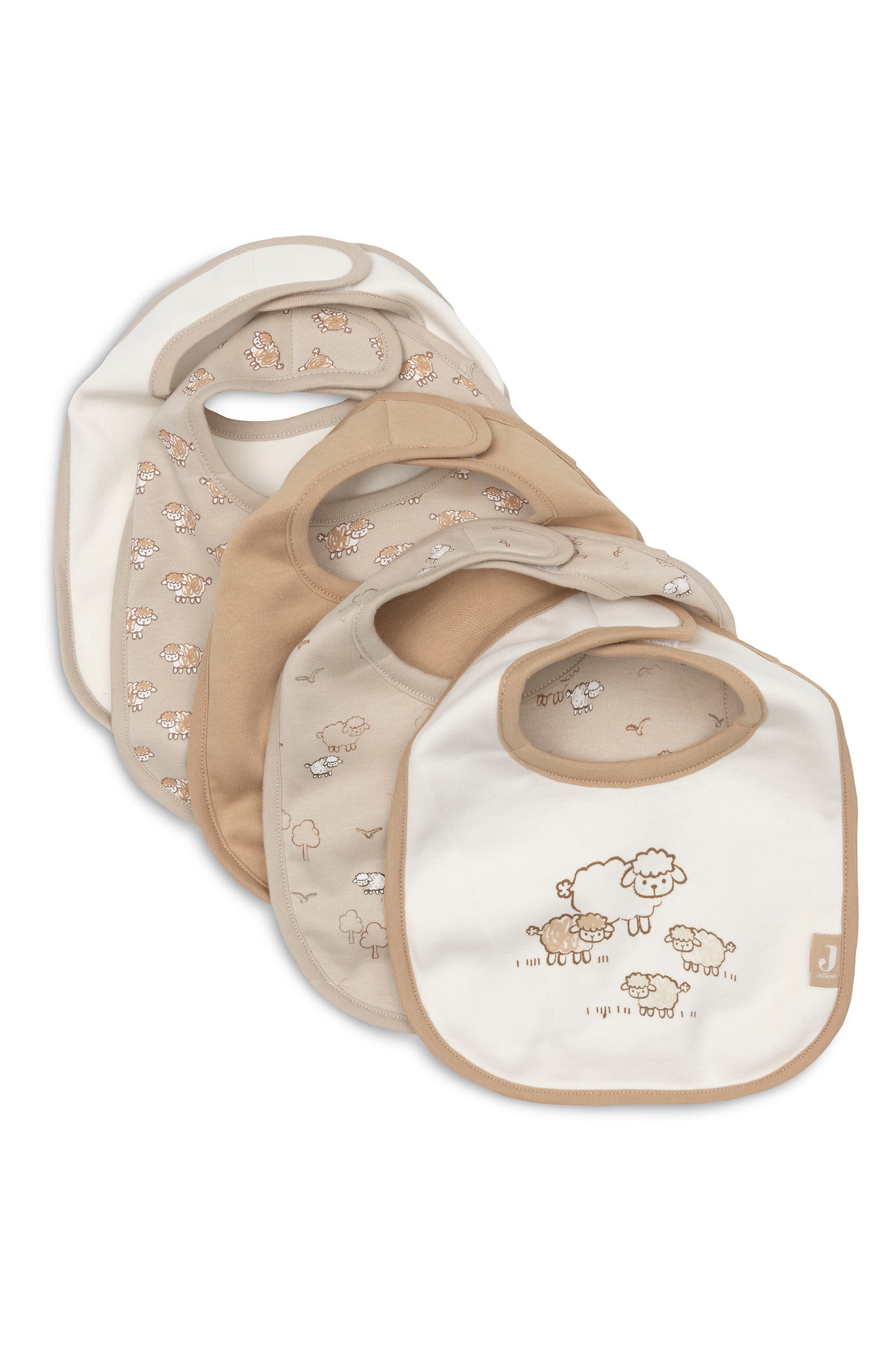 Een stapel slabbetjes voor baby's in crÃ¨me- en beigetinten ligt in een overlappende, waaiervormige opstelling, met verschillende ontwerpen, waaronder effen kleuren en cartoonachtige schaapillustraties. De slabbetjes hebben contrasterende stoffen randen en kleine beige labels met een gestileerd logo met de letter "J".