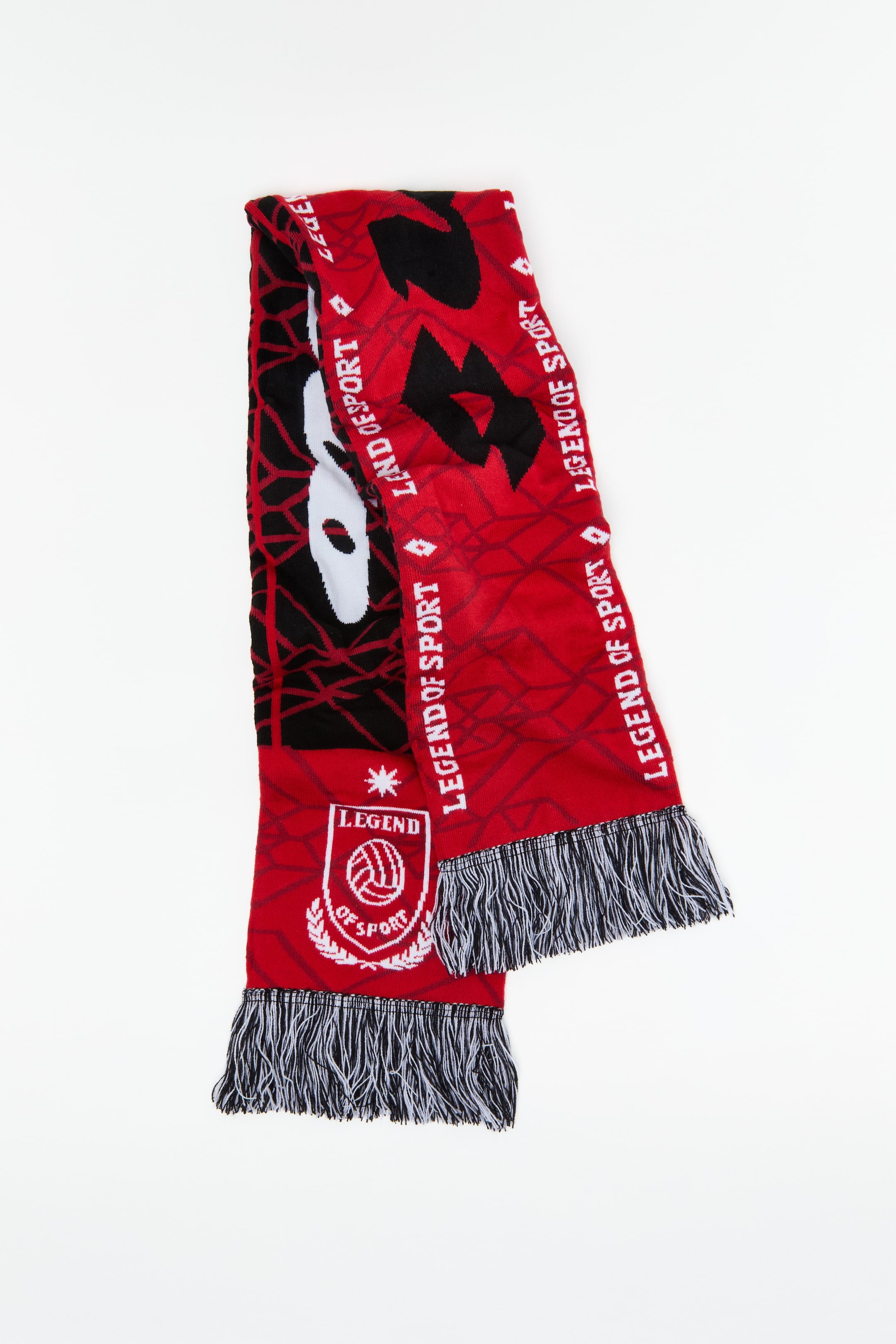 View larger image: A red, black, and white knitted scarf is laid flat, folded lengthwise. It showcases the repeating "LEGEND OF SPORT" text in white, a large stylised black and white graphic, and a white emblem featuring a soccer ball and laurel wreaths. Both ends are finished with black and white fringe.