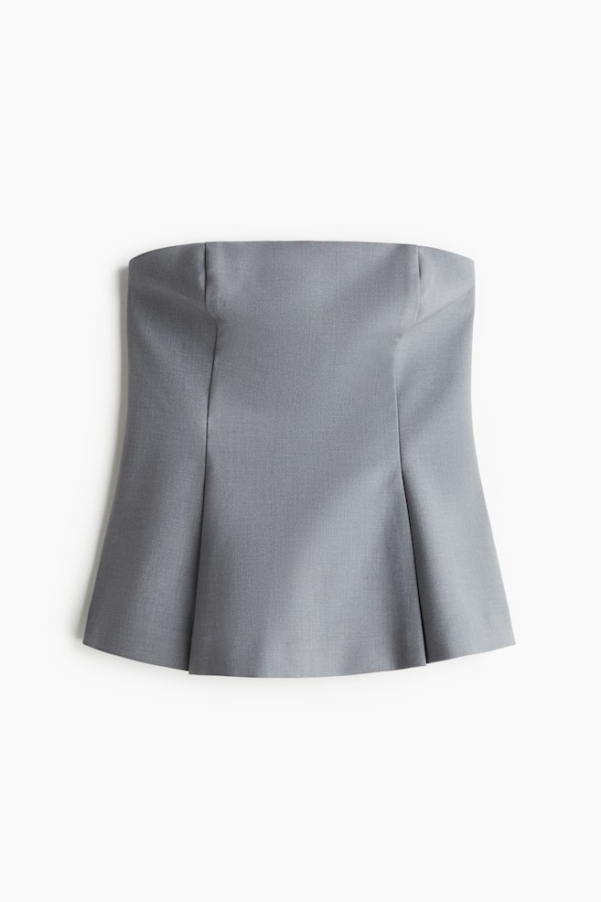 A grey strapless top is displaying a structured, fitted bodice with vertical seams extending into a flared peplum. - 1