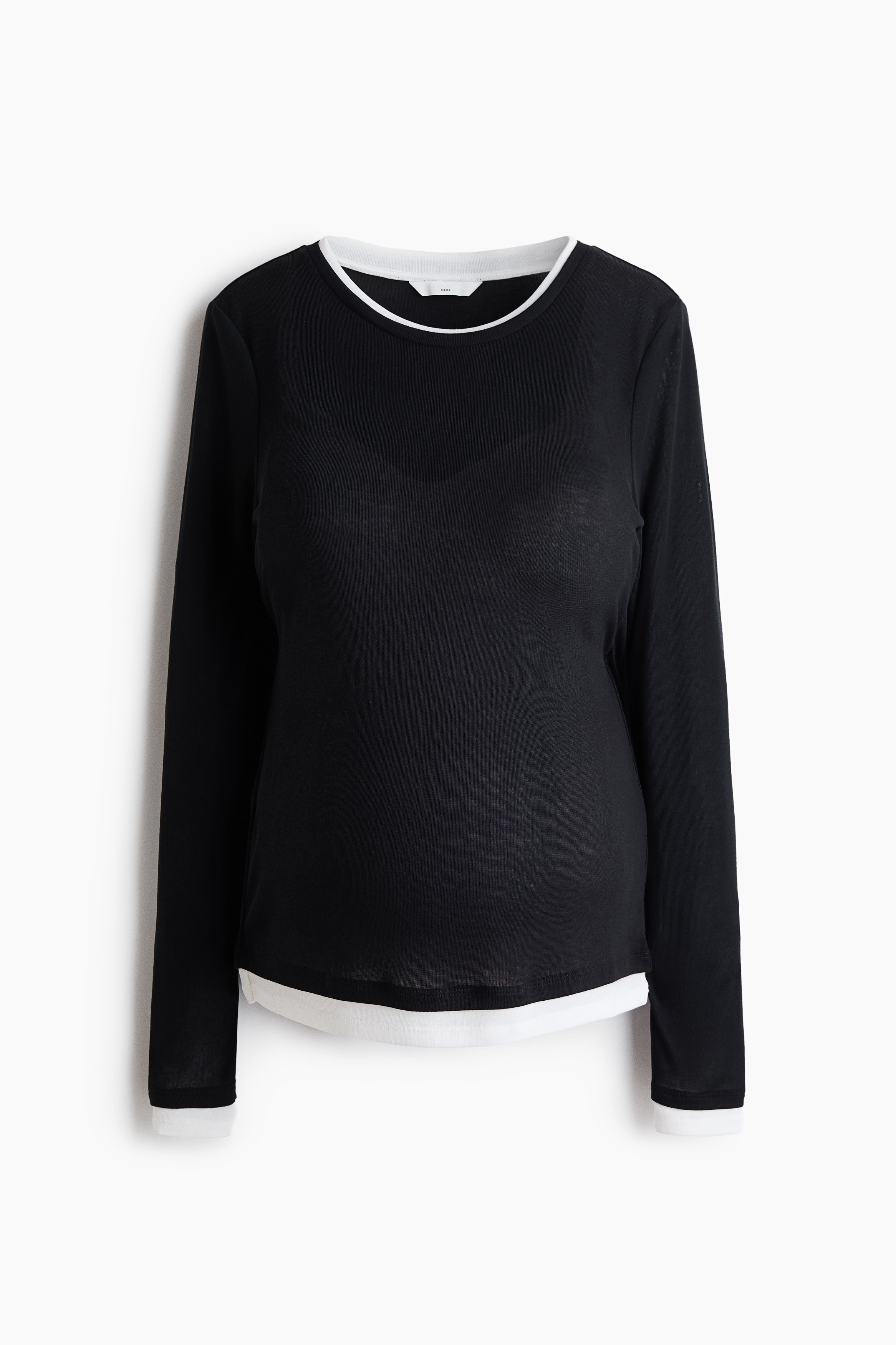 A black, fitted, long-sleeved top featuring contrasting white trim at the neckline, cuffs and hem is being worn by the model. The top is styled with wide-leg white trousers to complement the layered design.
