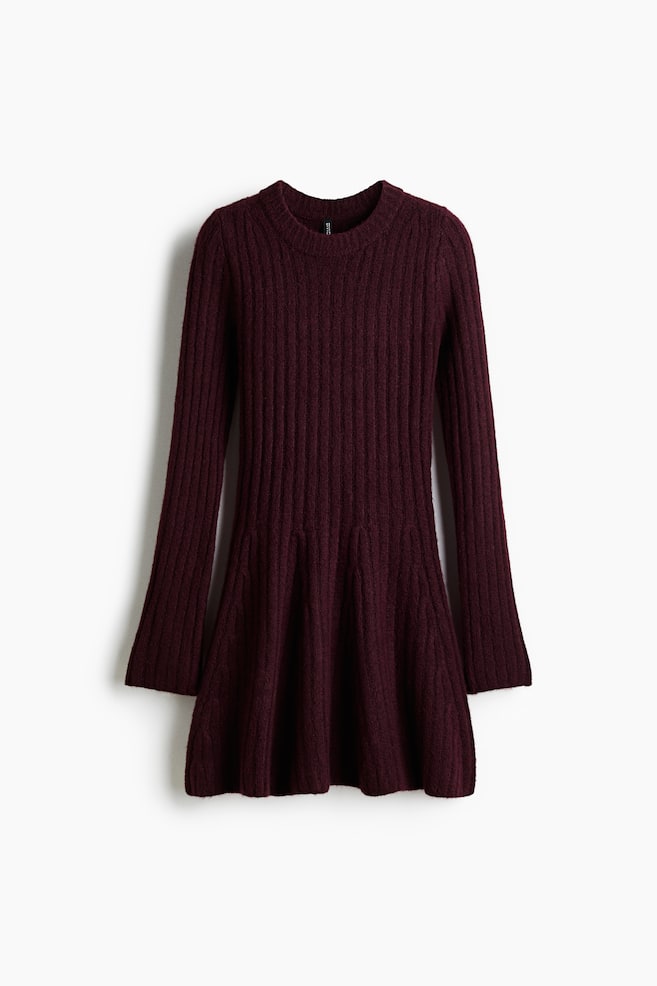 A burgundy knit dress is presenting a front view, featuring a ribbed texture throughout its upper body and long sleeves. The dress is designed with a crew neckline and is transitioning to an A-line skirt from the hip. - 1