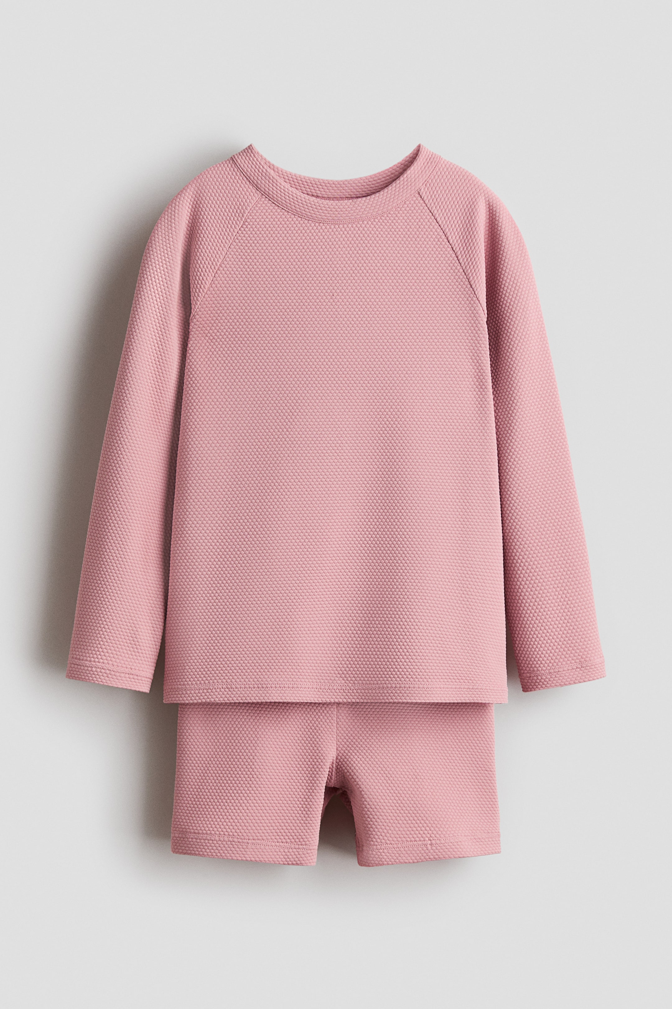 View larger image: The H&M Adorables swim set is presenting a front view of a pink, textured swim top and matching shorts. 