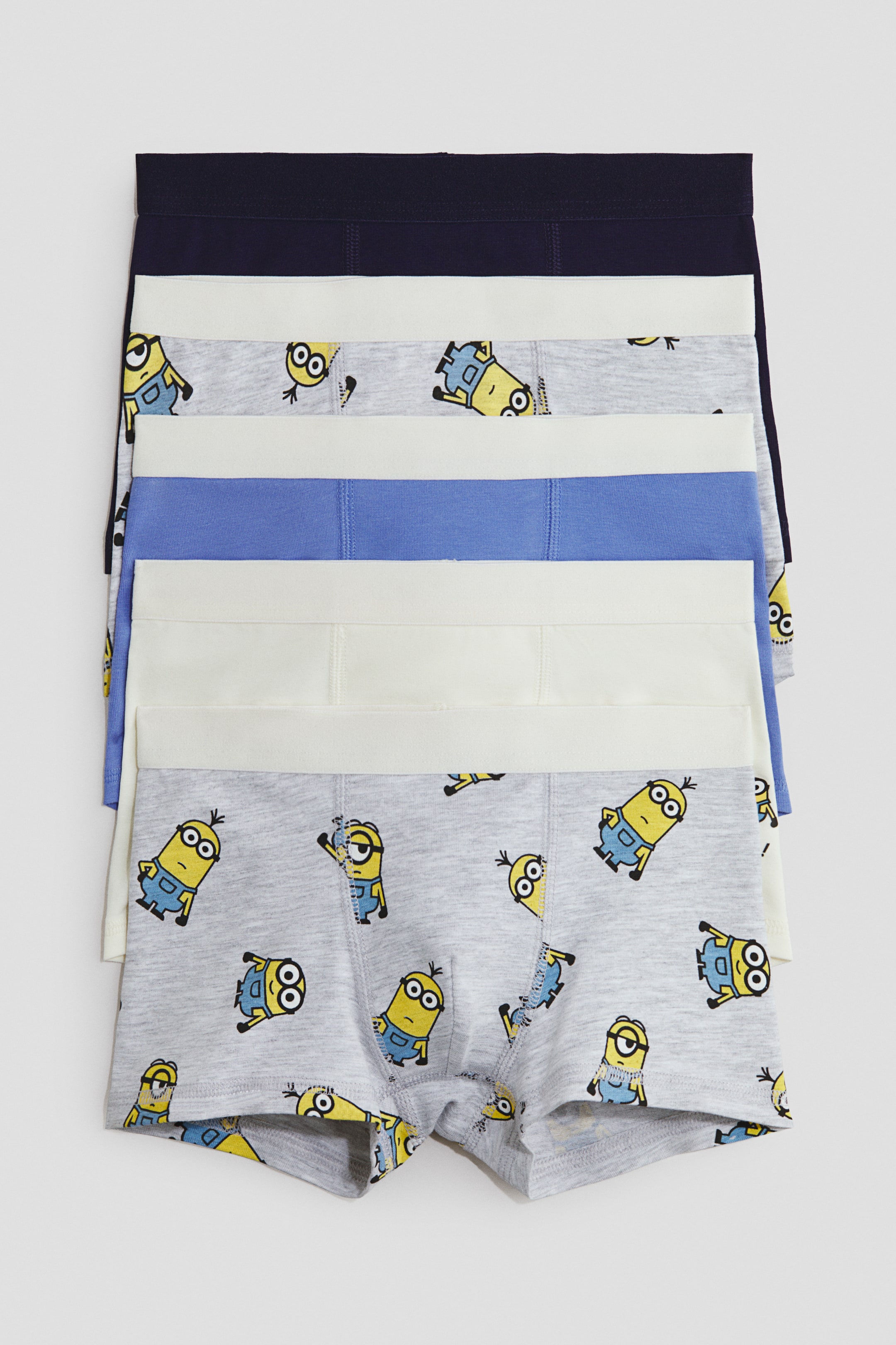 View larger image: Trunks in cotton jersey with short legs, an elasticated waist, and a lined front are stacked, presenting five pairs. The bottom pair is showing its full front in light grey with a Minions print, while the upper pairs are displaying their elasticated waists in navy, off-white, and light blue.