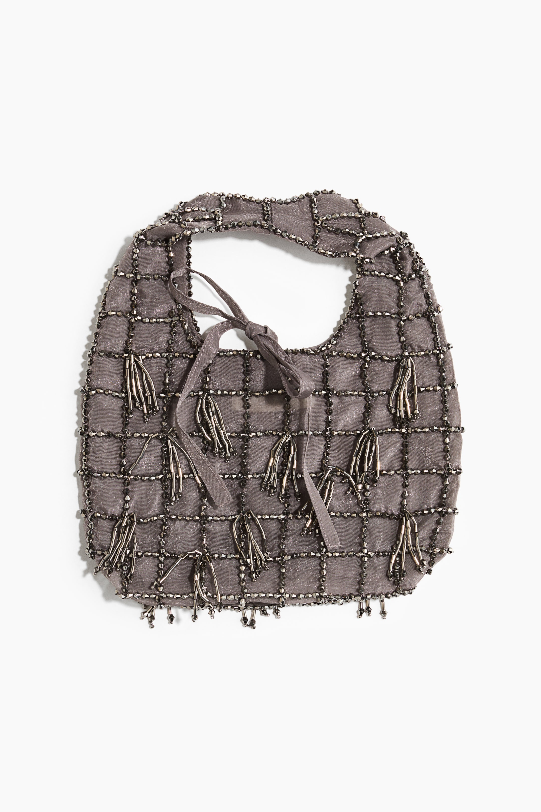 Ver imagen más grande: Se muestra un bolso de tela gris desde el frente, con un cuerpo semitransparente decorado con un patrón de rejilla de cuentas metálicas oscuras. El bolso presenta borlas de cuentas dispersas que cuelgan por su superficie y a lo largo del dobladillo inferior, con un cierre de lazo de cinta del mismo tejido a juego en la abertura superior.