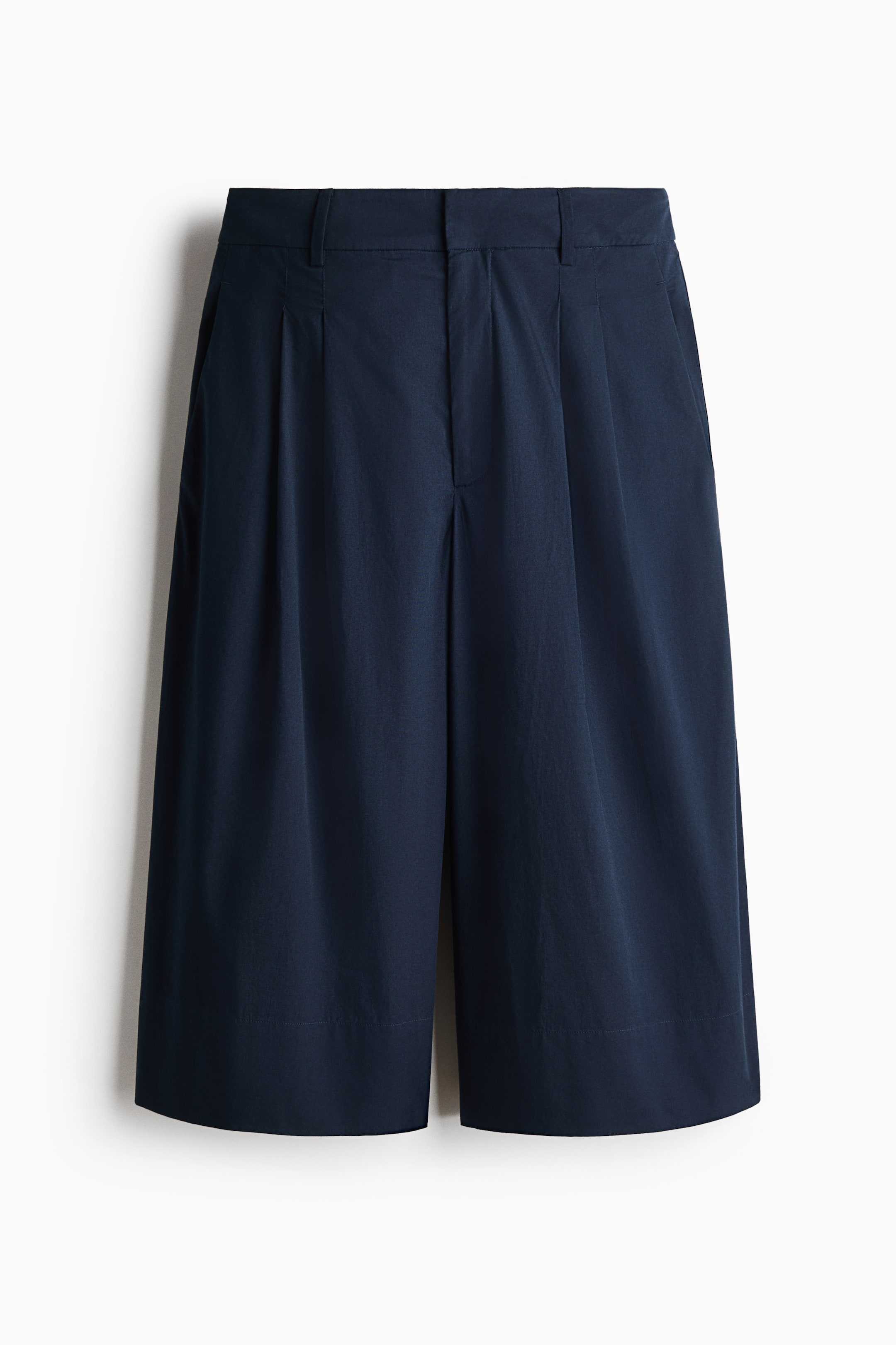 View larger image: Navy blue culottes are displayed from the front, showcasing a flat waistband with belt loops, a concealed zip fly, and double front pleats. Integrated side pockets are also visible, and the wide-leg silhouette extends to mid-calf.