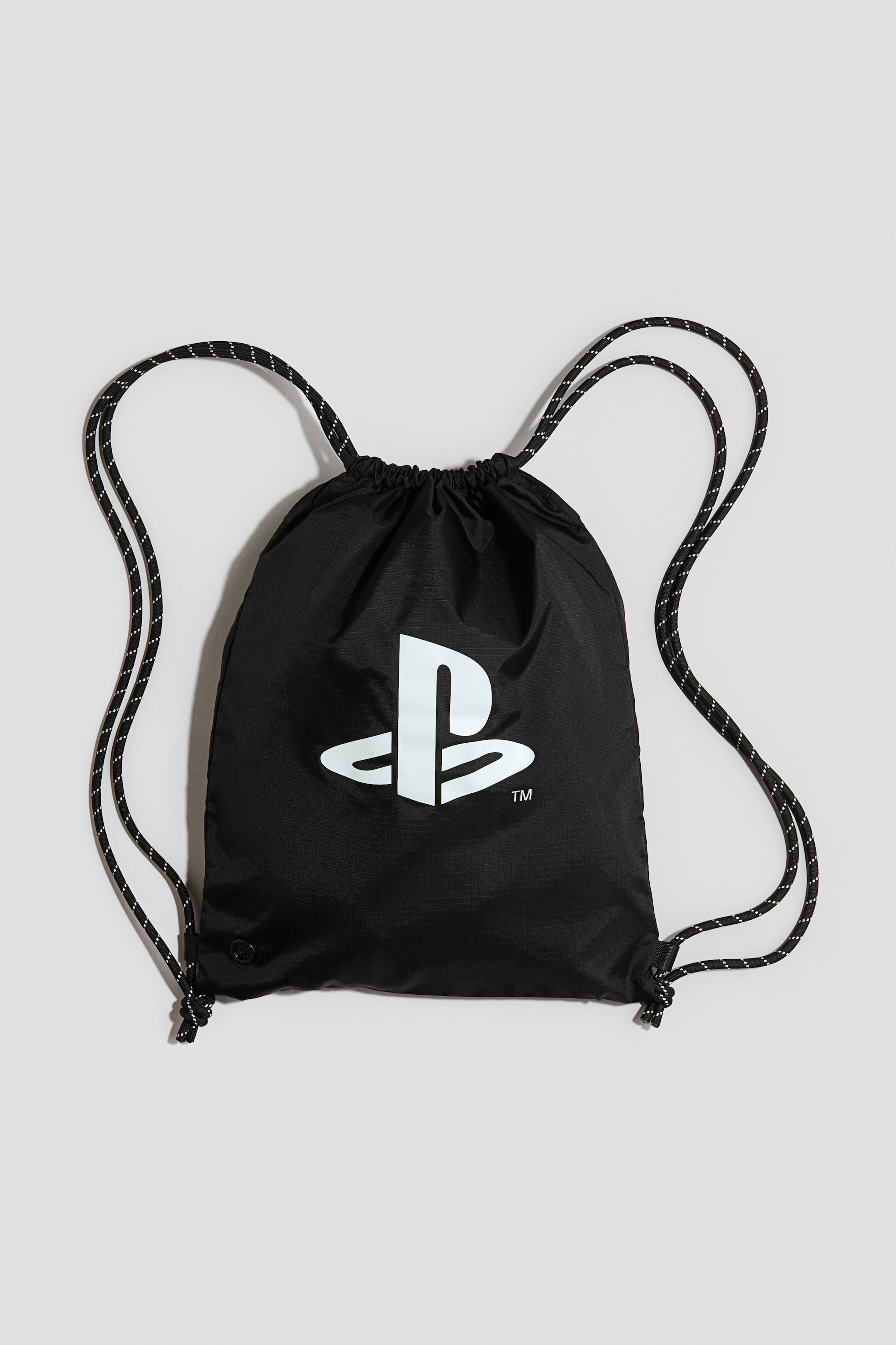 이미지 확대 보기: 검은색 드로스트링 가방 전면에 흰색 PlayStation 로고가 새겨져 있습니다. 검은색과 흰색이 섞인 로프가 드로스트링과 어깨끈을 형성하고 있습니다.