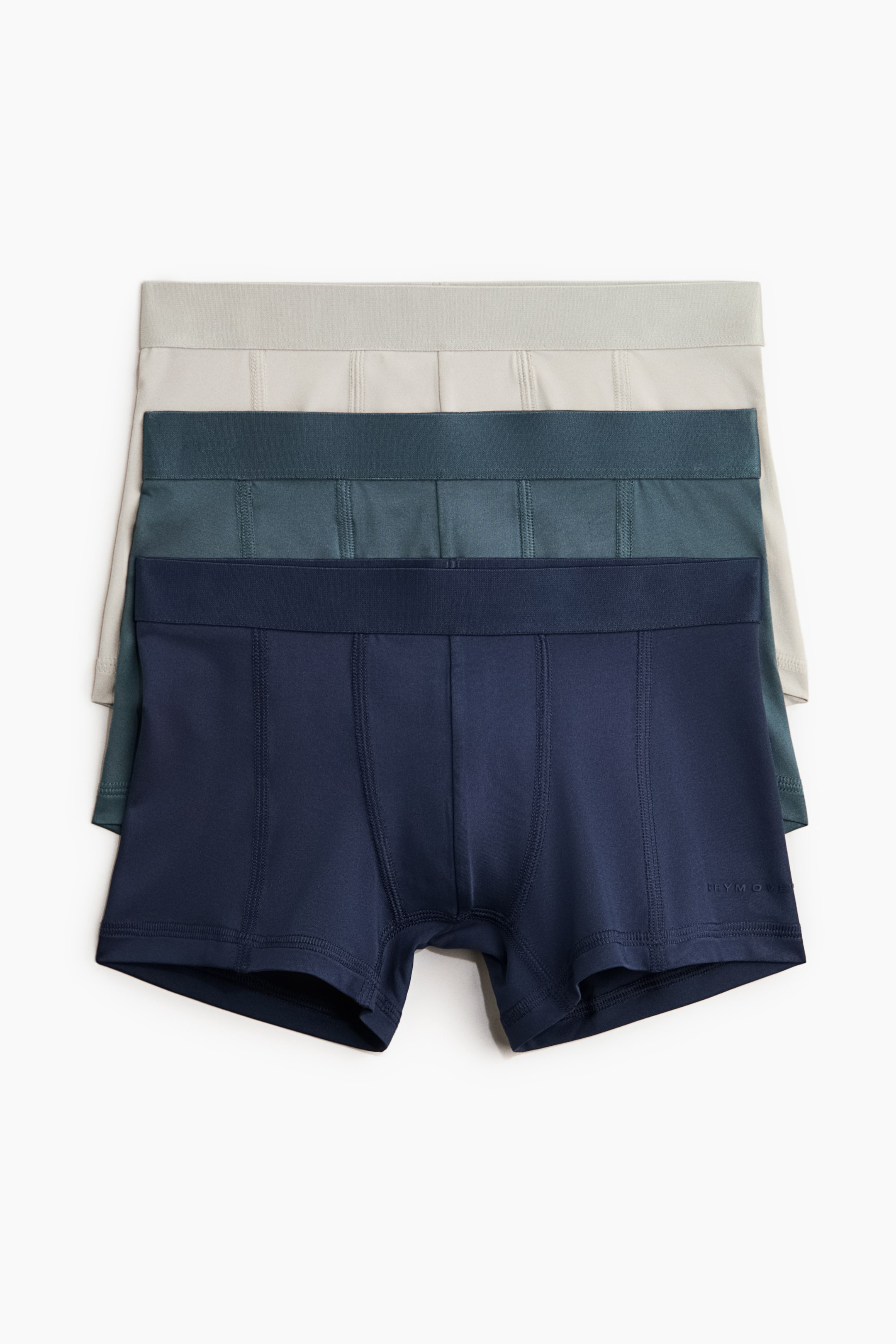 View larger image: Three pairs of boxer briefs are stacked, showcasing a light grey, dark teal, and dark blue colour palette from top to bottom, each featuring an elastic waistband and front stitching details on the leg panels.