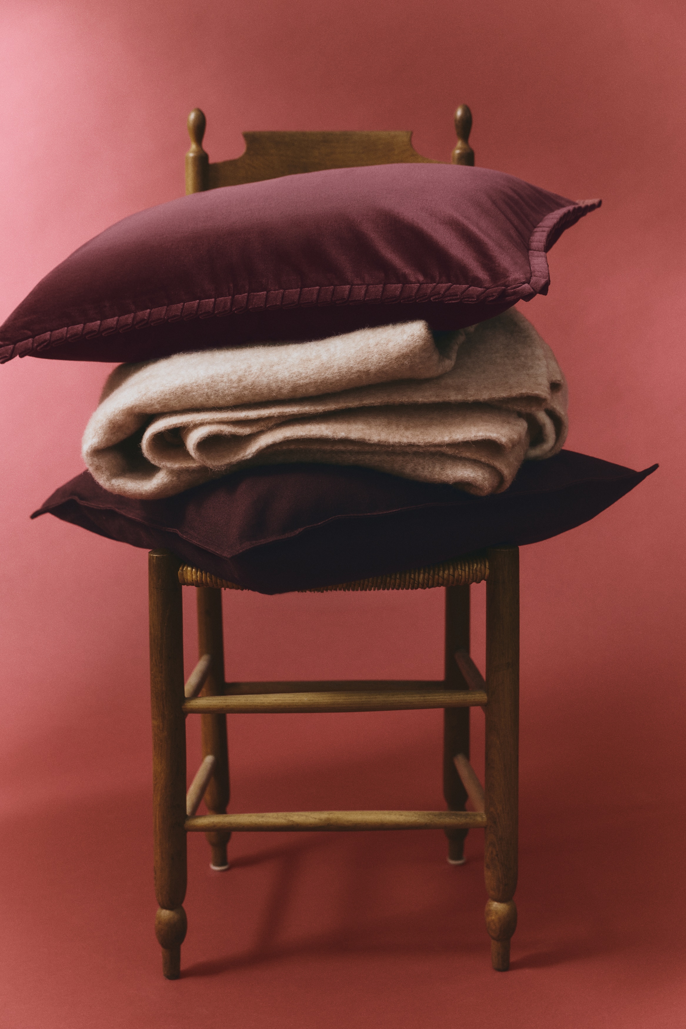 A rectangular velvet cushion cover in deep burgundy is shown from a front angle, featuring a soft, plush texture and pleated border trim along all four edges.