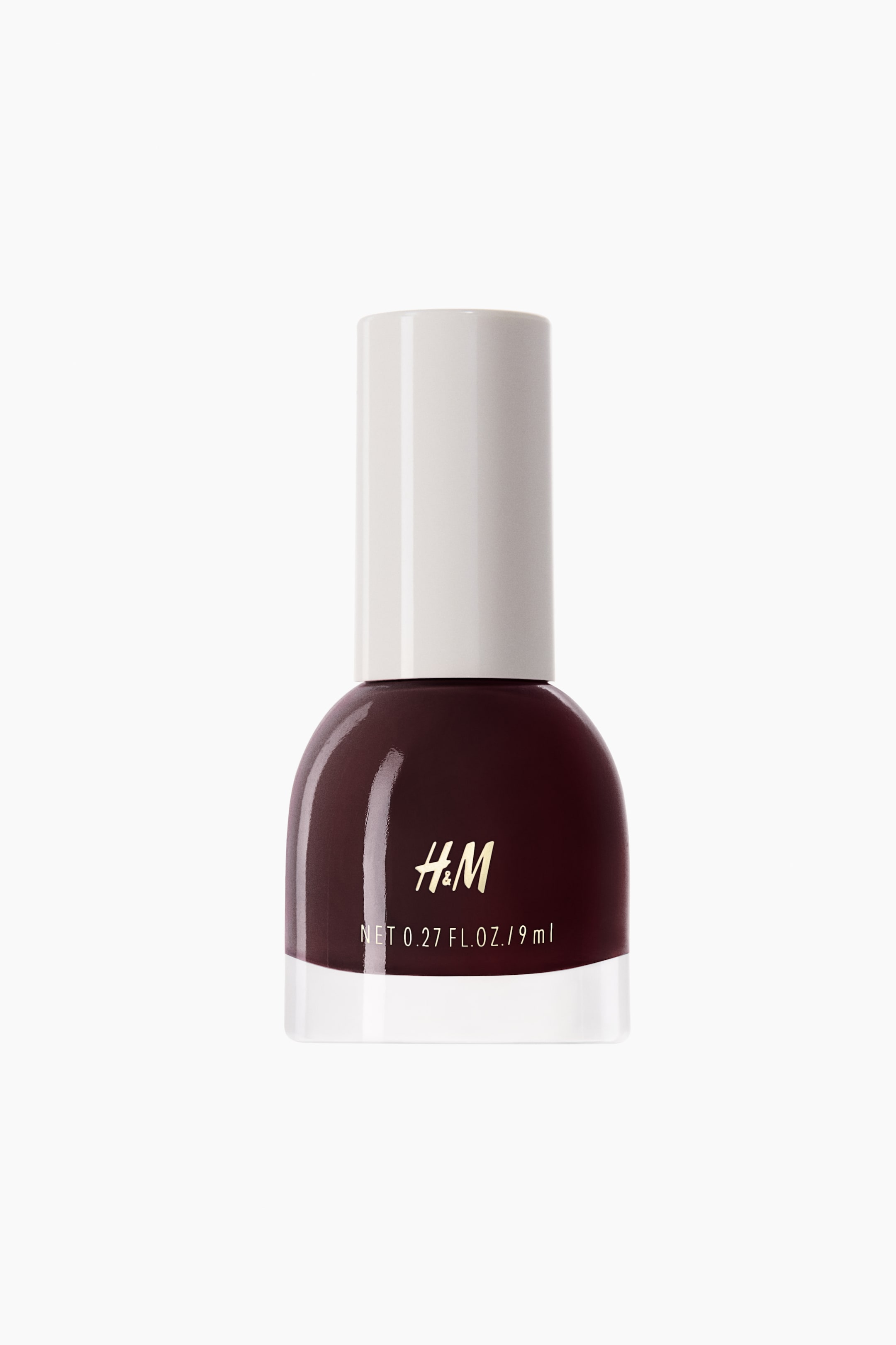 View larger image: Nail polish. The front-facing bottle is showcasing a deep maroon polish within a transparent glass base, topped with a white cylindrical cap. The H&M logo and net volume details are visible on the front.