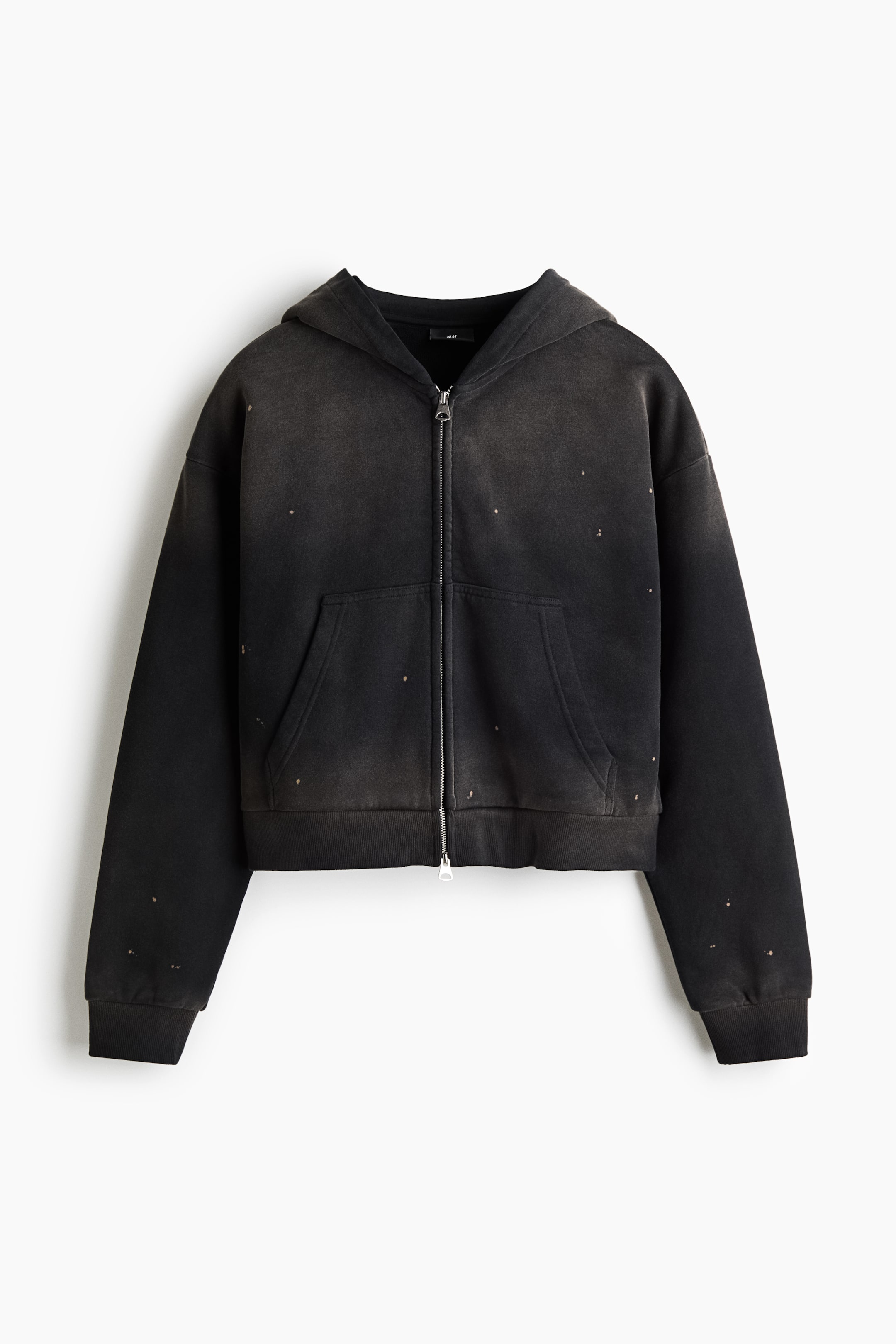 Xem ảnh lớn hơn: Một chiếc hoodie khóa kéo dáng hộp, oversized với màu đen wash phai được chụp từ phía trước, nổi bật với vai trễ, khóa kéo hai chiều màu bạc và túi kangaroo tách đôi. Chất vải dày dặn thể hiện những chi tiết rách mòn tinh tế xuyên suốt bề mặt, hoàn thiện với bo tay và gấu áo bo rib.
