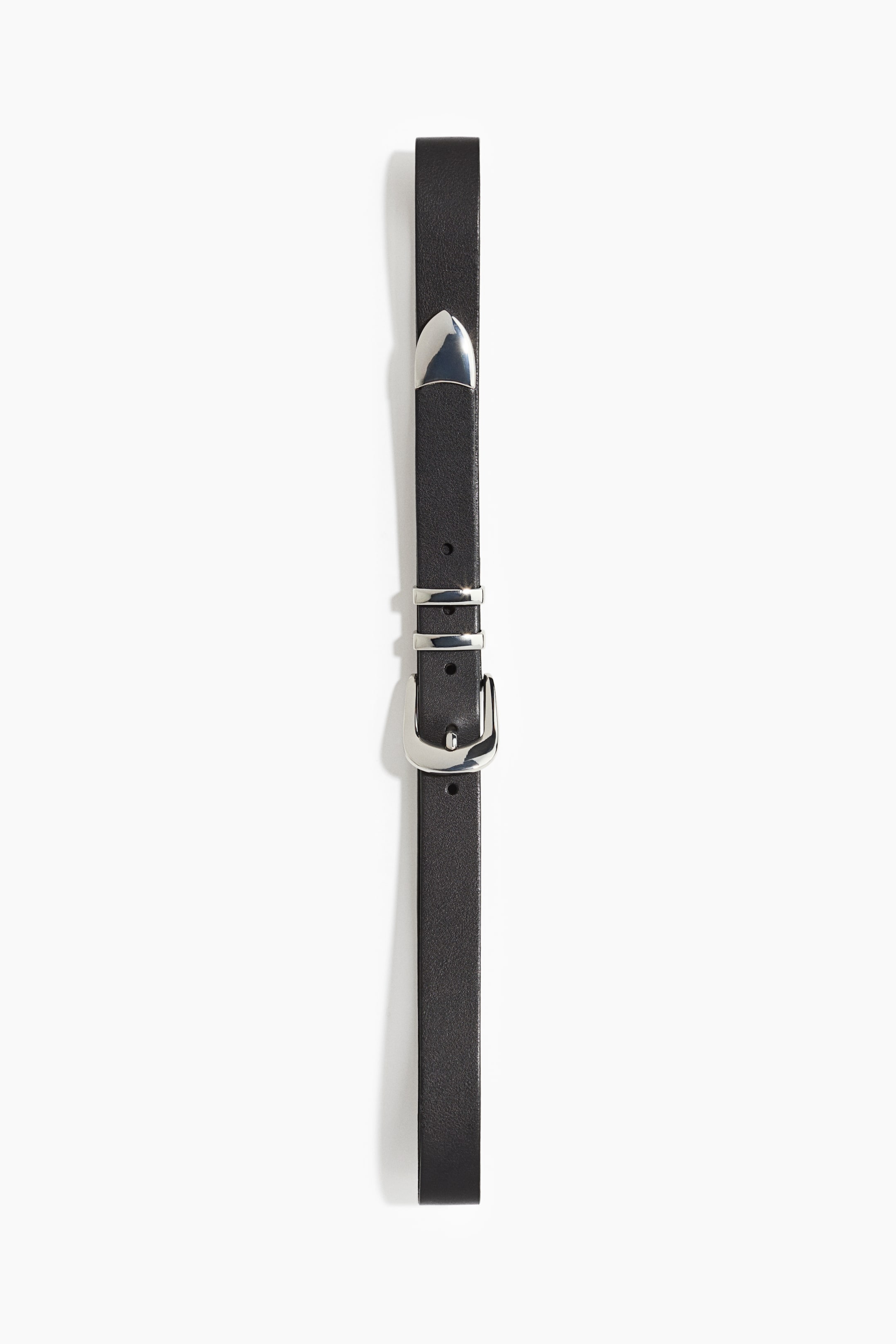 View larger image: A slim black leather belt is shown vertically, featuring a polished silver-tone Western-style buckle, double metal keepers, and a pointed metal tip. The strap has a smooth matte finish with pre-punched sizing holes.