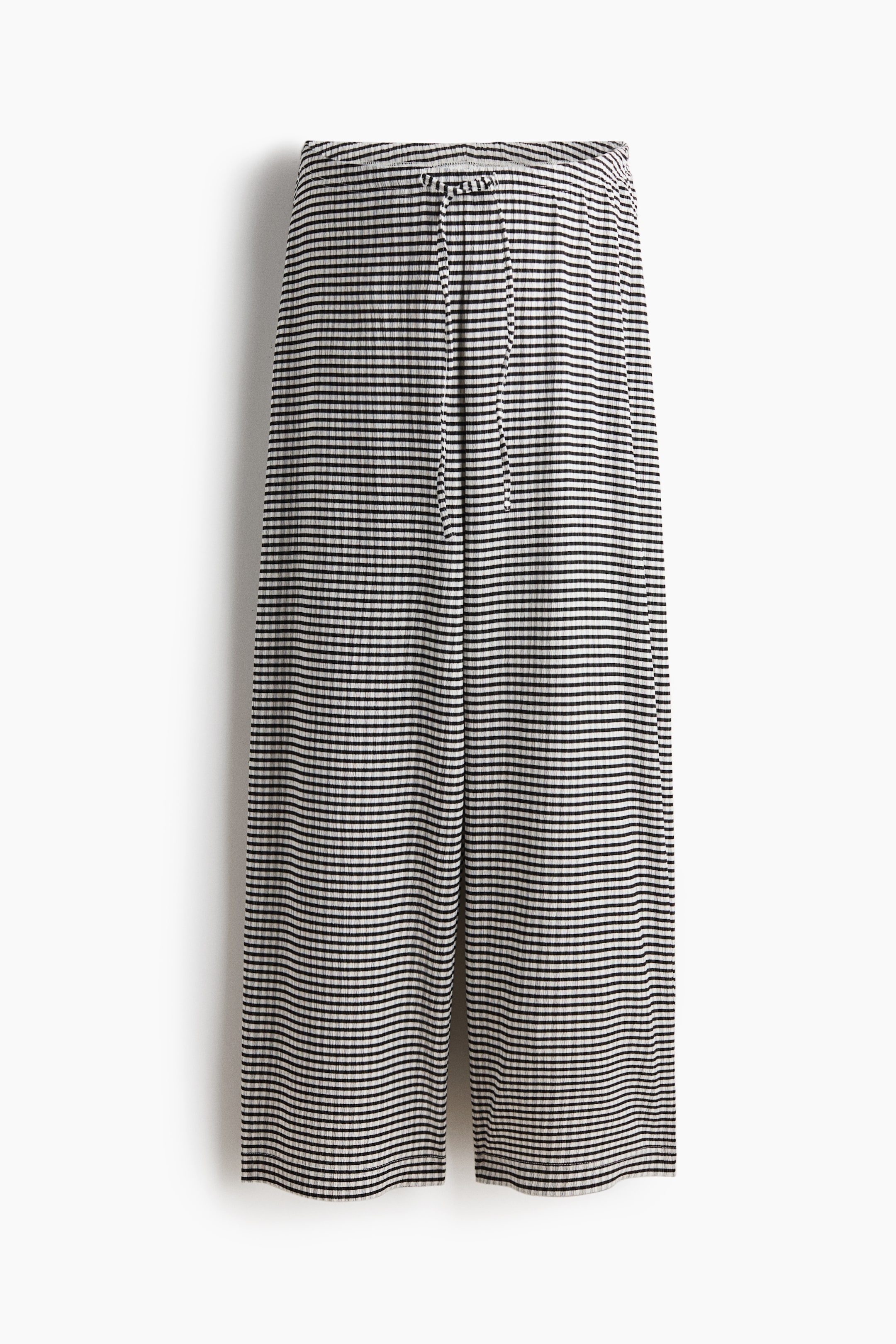 Größeres Bild ansehen: Die Hose zeigt ein horizontales Muster aus schwarzen und cremeweißen Streifen auf einem gerippten Stoff. Sie verfügt über einen Kordelzugbund und einen weit geschnittenen, verkürzten Beinabschluss.